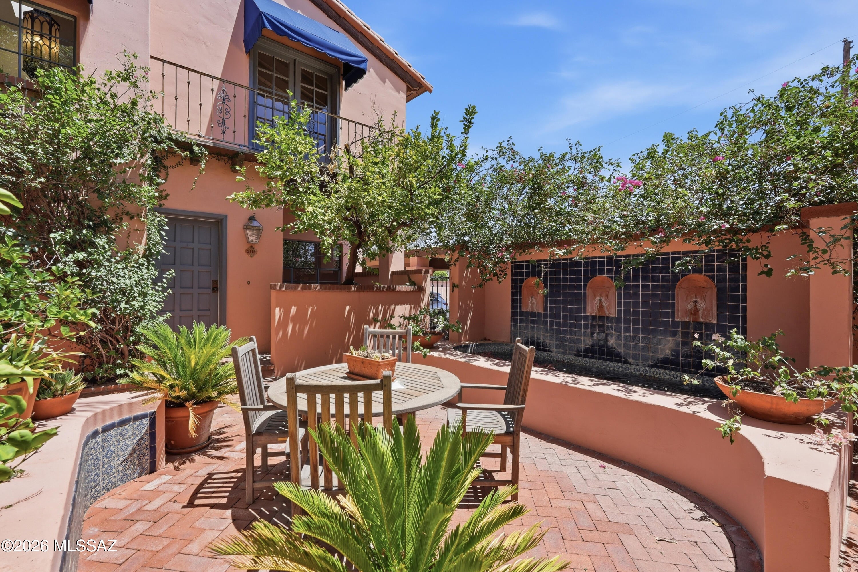 Old World Charm nestled between Sam Hughes & El Encanto. La Querencia is an exclusive community of only 8 townhomes, built  by John Hornburg, conveniently located 1 mile east of the University of Arizona. Enter through the antique gate to a lush courtyard with mature landscaping, tranquil waterfalls and seating areas. Inside the home you will find soaring wood beamed ceilings, cozy beehive wood fireplace, Saltillo tile leading to the outdoor private patio. Spacious primary bedroom with walk-in closet and Juliette balcony overlooking the beautiful courtyard. Second bedroom with bay-window seating with some mountain views. Roof 2023 & HVAC 2025.