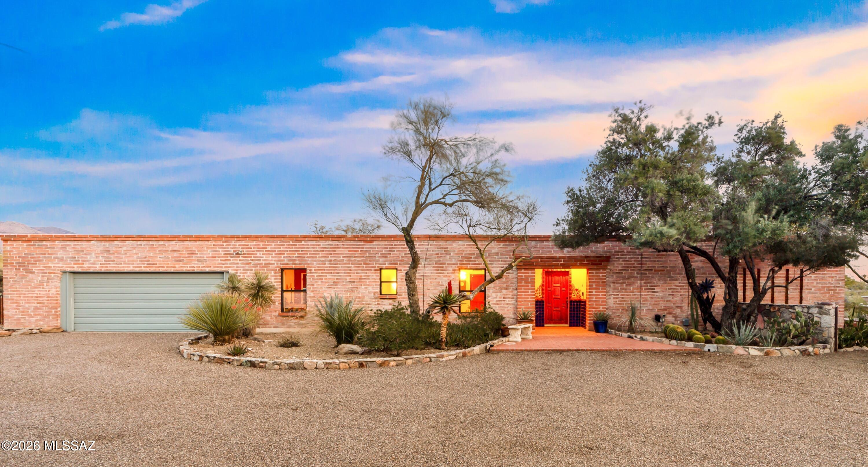 Classic burnt adobe architecture defines this privately situated 1.26-acre estate in the highly desirable Catalina Foothills Estates No. 7, surrounded by the lush beauty of the Sonoran Desert. A handcrafted wood entry door accented with vibrant Talavera tile sets the tone for the warmth and authenticity found throughout. Inside, rich beamed and plank ceilings pair beautifully with a charming corner beehive fireplace, while French doors invite natural light and frame peaceful patio views, creating a seamless indoor-outdoor connection. The updated kitchen offers crisp white cabinetry, some with glass fronts, a central island, and striking black solid-surface countertops, blending timeless character with modern functionality. The detached 540 sq. ft. studio casita, built in 2019, provides exceptional flexibility and privacy. Nestled within its own desert sanctuary, it features polished concrete floors, a kitchenette with solid-surface counters and an attractive tile backsplash, and a spacious full bath. A private path leads to a tranquil sitting area with a stone fire pit, perfect for guests, creative space, or multigenerational living.
Outdoors, a covered patio and thoughtfully curated seating areas are woven throughout the expansive grounds, offering both privacy and a serene connection to nature. Enjoy Tucson's legendary sunsets, sweeping desert skies, and the peaceful rhythm of foothills living.
Ideally located just minutes from Rillito Park Farmers Market, St. Philip's Plaza, La Encantada, Trader Joe's, and an array of local dining favorites, this residence beautifully blends charm, privacy, and convenience in one of Tucson's most coveted locations.