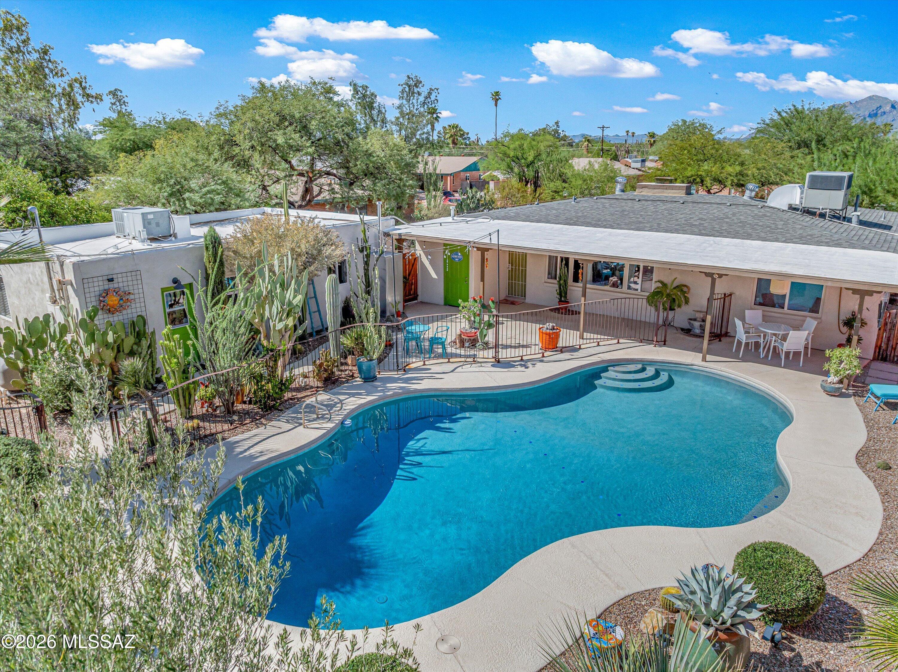 This tucked-away home has a backyard oasis and its own guest house, both fully updated and move-in ready.  In a quiet pocket of Central Tucson, the main house offers 3 beds, 2 baths, a kitchen with real cabinet space, and a wraparound driveway. Step out back to a recently resurfaced PebbleTec pool, with a newer pump and filter. Around it, years of curated desert plantings have grown into something closer to a botanical garden than a yard. Warm painted walls, a covered patio strung with lights. Everyone ends up out here. The guest house stands fully on its own. 2 bed, 1 bath, full kitchen, laundry hookups, off-street parking, private entrance, and backyard access. Live in one and rent the other, host short or long term, or keep it for visitors. Close to UA, Banner, grocery, and restaurant