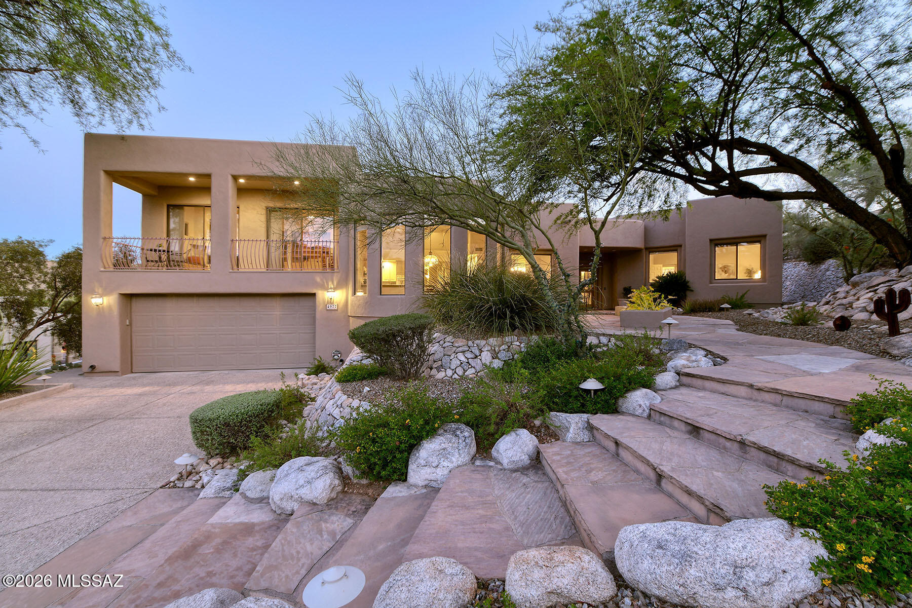 Located in the prestigious gated Ventana Ridge community, this 3,487 sq. ft. home offers stunning Catalina Mountain views from the front and Rincon views from the back. Set on .43 acres, the beautifully landscaped property features a walled backyard with natural grass, fruit trees, multiple saguaros, and an extended covered flagstone patio with several seating areas. Inside are 4 bedrooms, 2.5 baths, formal living and dining rooms, and a raised family room with a gas fireplace and view balcony. The spacious kitchen boasts granite countertops, double ovens, gas cooktop, walk-in pantry, and mountain views. Smart home technology, built-in speakers, a tandem 3-car garage, and a luxurious primary suite with patio access complete this exceptional home near Sabino Canyon, hiking, and dining.