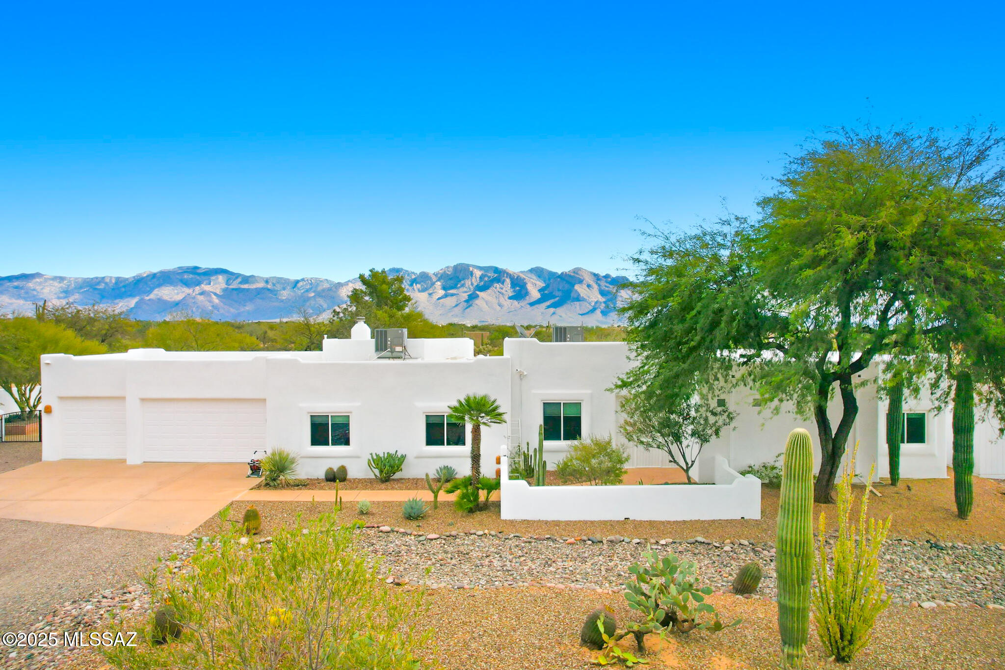 Stunning custom 4-bed, 3-bath home on 3.33 acres with breathtaking Catalina Mountain views. Gated entry opens to a serene desert oasis with authentic Santa Fe details throughout. Soaring 9 ft ceilings, 2 fireplaces, skylights, ceiling fans & transom windows bring in natural light. Bright chef's kitchen boasts white cabinetry with pull-outs, quartz counters, pantry & breakfast bar. Sliders lead to the expansive 60-ft east-facing covered patio perfect for entertaining. Spacious master suite features a sitting area, sliding glass door to patio & luxurious updated dual vanity en-suite. Exterior painted 2025, all new carpet, wood plank tile, new windows & sliders, roof recoated 2023, fruit trees with drip irrigation, detached shed & epoxy-finished 3-car garage. A true gem, a must see.