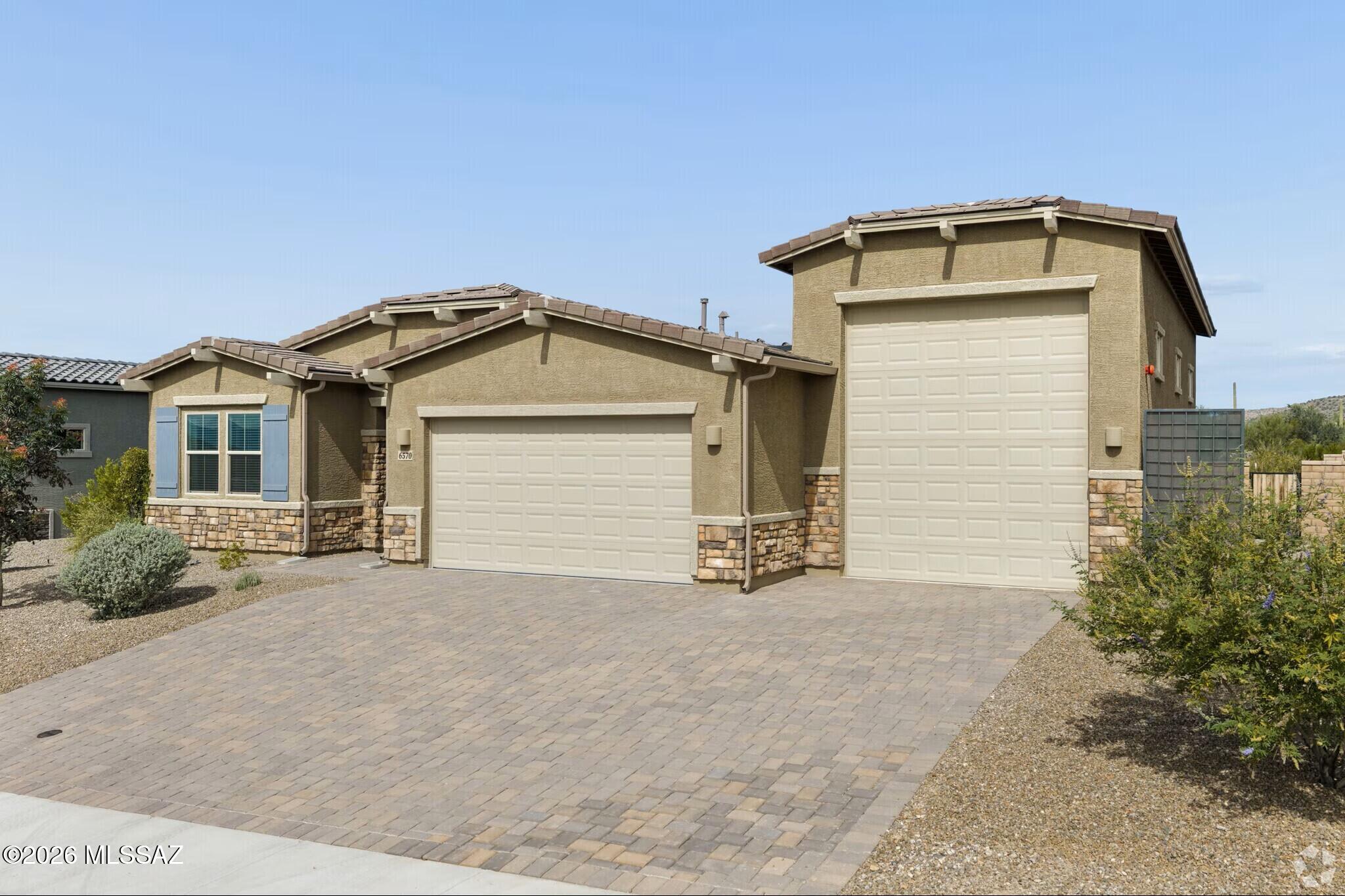 Nestled in the breathtaking foothills of the Tortolita Mountains lies Los Saguaros at Dove Mountain, an exclusive gated community hosting this exceptional 2023-built single-level residence. Perfectly positioned for golf enthusiasts, the property borders the prestigious Golf Club at Dove Mountain, Saguaro Golf Pass destination. As a former model home, this 4-bedroom, 2.5-bathroom estate showcases an array of high-end, elegant features throughout its thoughtful, single-story floor plan. The heart of the home is a chef-inspired kitchen adorned with rich granite countertops, a premium stainless steel appliance suite, and a sleek integrated microwave into the bottom cabinets. This bright, open interior transitions seamlessly to a massive, super-tall attached 3-car garage that comes completely ready to house your luxury RV, trucks, or weekend toys. Step outside into an entertainer's dream come true. The private backyard oasis is framed by tall, mature Saguaro cacti and panoramic Tortolita Mountain views. It features an upscale outdoor kitchen, a cozy fireplace for crisp desert evenings, a relaxing water fountain feature, and stylish modern pavers. Best of all, the lawn is finished with Arizona's favorite synthetic turf, promising a vibrant green look year-round with absolutely zero watering required. Wind down on your back patio and soak in world-class Southern Arizona sunsets from this ultimate desert retreat.