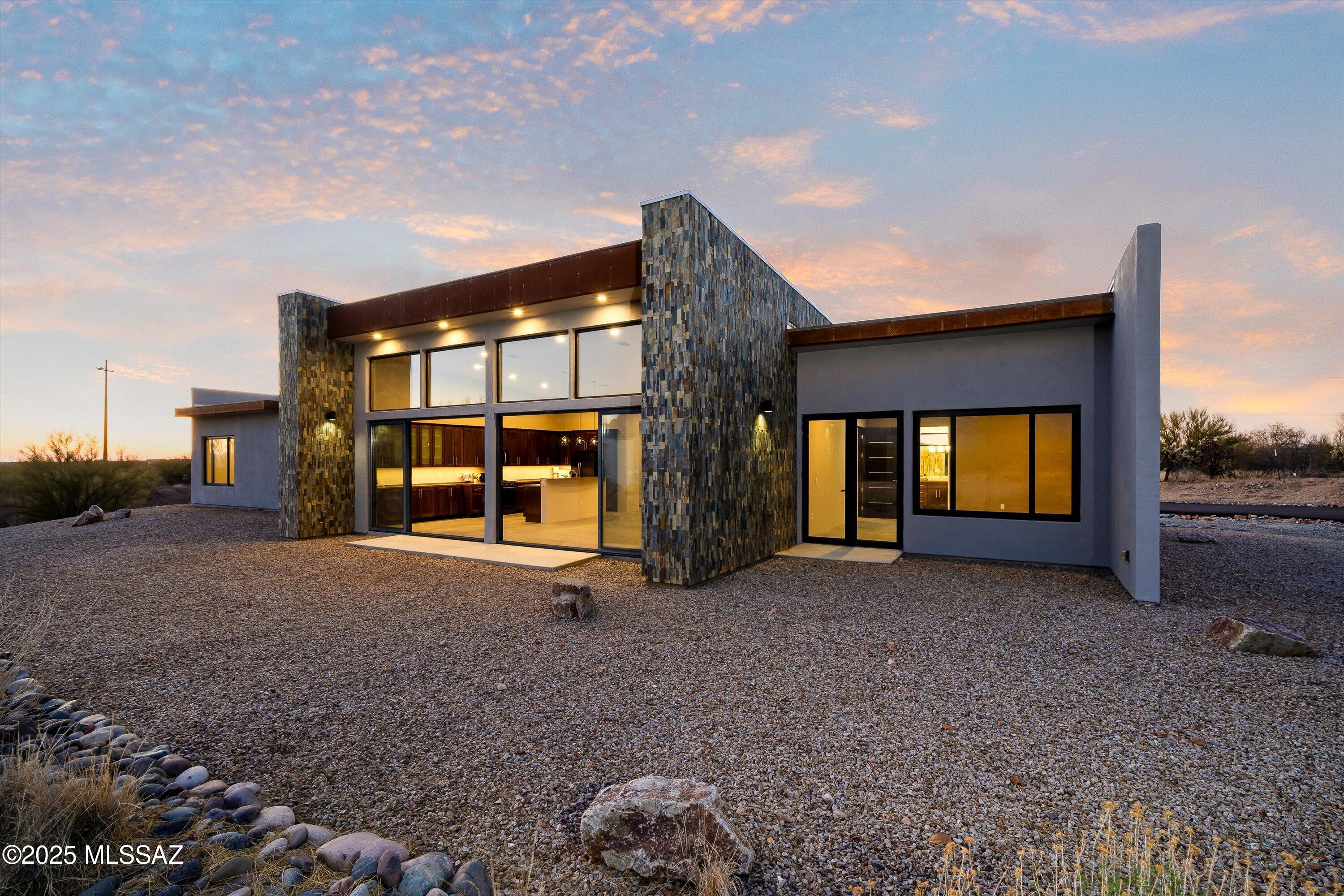 Welcome to North Dust Devil Drive, where the mountains aren't just a view—they're your backyard. Designed by SBBL Architecture with site layout by architect Rob Bass to maximize views and energy efficiency, this 4-bedroom, 3.5-bath contemporary retreat spans over 3,000 square feet on a full private acre with no HOA.
Dramatic custom metal entry doors open to reveal where contemporary architecture meets the raw beauty of the Sonoran Desert. The striking exterior showcases a masterful blend of stacked stone, sleek stucco, and metal accents—the stone-covered parapeted foundation walls creating the same visual angles as the mountains themselves, casting shadows that mimic the Catalinas at sunset.
Step inside where concrete floors flow seamlessly through every room—low-maintenance, durable, and perfectly suited to desert living. The great room captivates with dramatic vaulted ceilings soaring to 13 feet and walls of commercial-grade windows featuring double pane, argon-filled tempered glass with superior UV protection. The home's strategic orientation maximizes winter sun while minimizing summer heat gain smart passive solar design. The sliding glass doors erase the boundary between inside and out, creating a seamless flow perfect for entertaining against Arizona's legendary sunset backdrop. Recently installed weatherproof shutters mean you can button up for monsoon season or when you travel, then open back up to those views that never get old. 
The chef's kitchen is where functionality meets sophisticated design. Premium birch wood shaker-style cabinetry with sleek hardware provides storage and striking contrast against gleaming high-end stone countertops strategically positioned to maximize mountain views. Contemporary slate stainless appliances blend seamlessly while a generous island becomes the natural gathering spot. Custom built-in buffet cabinets along the dining area wall define the space beautifully. The eat-in area offers mountain views, and even that sink overlooks the Catalinas.
Your primary suite is tucked into a split-bedroom floor plan for complete privacy. Imagine starting each day with mountain views, then stepping through sliding glass doors to your secluded patio. The spa-worthy bathroom features a dramatic floor-to-ceiling stacked stone feature wall in carefully selected light neutral tones, sculptural freestanding tub, and oversized glass shower. The custom walk-in closet system with rich wood finishes is beautifully organized.
Three additional bedrooms give you options for guests, office, gym, or whatever your life requires. One features its own ensuite bath with mountain views and walk-in showerperfect for visitors or multi-generational living. Two more bedrooms share the third full bathroom. Throughout the home, superior construction includes 2"x6" framing for exceptional structural integrity and noise reduction, high-density roof insulation, and heavy 8-foot custom wood composite doors.
An architectural standout: the impressive 6-foot wide main hallway with a window at the end that bathes the entire corridor in orange light at sunset transforming what could have been ordinary into something dramatic.
Here's what makes this property truly rare: that full acre on the outskirts of Oro Valley, with these views, and no HOA. The spacious three-car garage handles your vehicles while RV parking means your adventure mobile is always ready. Build the pool you've dreamed about. Add a guest casita. Create an outdoor kitchen and entertaining areas. Or preserve the pristine desert landscape and watch quail families parade through while javelinas root around at dusk.
You're minutes from Oro Valley's best shops and restaurants, yet you feel a world away. Catalina State Park and Coronado National Forest beckon with endless hiking, mountain biking, and exploration. Natural gas service and paved road access provide modern conveniences in this serene setting.
This isn't just a houseit's a lifestyle. Contemporary luxury meets desert tranquility, where every window frames a postcard-worthy view, and where your vision for desert living can unfold without limitation.
Come experience what it means to have the Catalinas as your backdrop for everyday living. Schedule your private tour today!