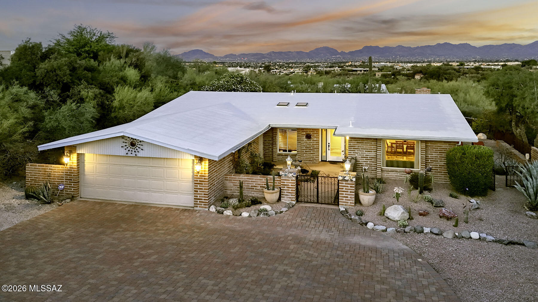 Authentic burnt adobe home nestled in the highly desirable Cat 7 neighborhood, offering breathtaking sunset and Catalina Mountain views. A gated courtyard creates a warm and inviting entry, leading into a thoughtfully designed interior featuring rich Rogo concrete overlay flooring throughout. The living and dining areas are highlighted by expansive picture windows that beautifully frame the mountain backdrop. The kitchen blends modern updates with timeless hacienda charm, showcasing a large concrete-topped island, tile accents, refaced cabinetry, and a new Bosch dishwasher, all opening seamlessly to the family room with a classic beehive fireplace--perfect for gathering and entertaining. Spacious guest rooms provide flexibility, with one currently serving as an office, while the guest bath impresses with a striking copper sink and tiled counters. The Primary Suite offers a peaceful retreat with a large walk-in closet, dual sinks, a travertine tiled shower, and private patio access. Step outside to a truly stunning backyard featuring majestic saguaros, lush desert landscape , fruit trees, a covered BBQ and cooking area, and ample space to relax, play, and soak in the incredible views.