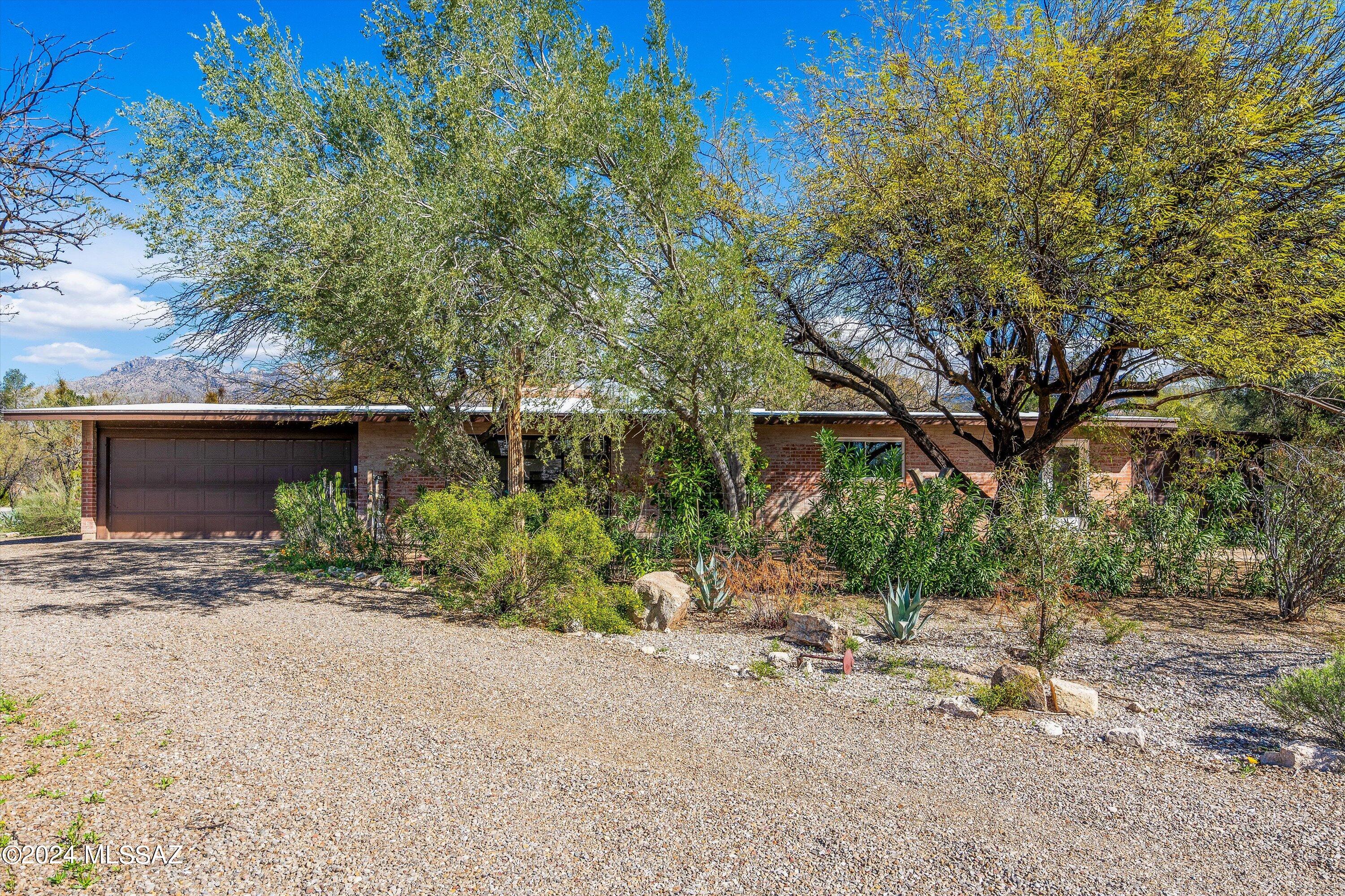 Welcome to 8801 E Buckboard Rd.  From the moment you enter it will feel like home! This Ranch style house offers a modern twist with 3 spacious bedrooms and 2 updated baths. Features include a beautiful kitchen with brand new SS appliances, pass thru fireplace, concrete floors throughout, spacious living room opens up to the outdoor flagstone courtyard, 2 car garage + half circle driveway, RV spot with full hookups and the enormous backyard (half acre total property) offers an authentic custom built pizza oven & views of the mountains. Extra bonus room/storage area. Located in Northeast Tucson near Mount Lemmon, hiking, biking, shops, restaurants and more.