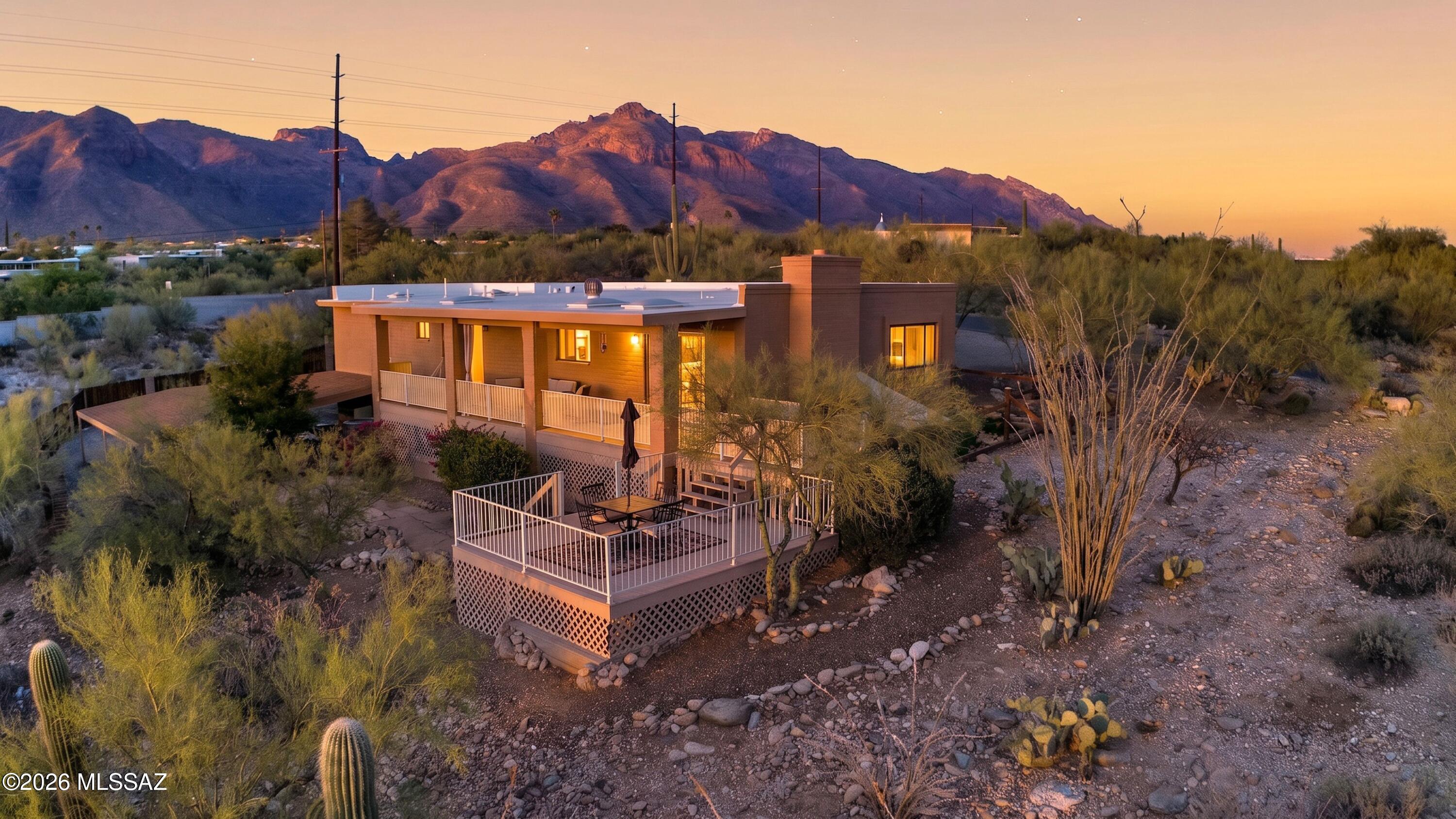 Perched in the desirable Vista De Las Candelas Estates within the Catalina Foothills, this charming and unique residence captures stunning mountain vistas by day and sparkling city light views by night. Situated on .83 acres, the property offers exceptional privacy, generous parking, and room for recreational vehicles, a seemingly rare find in these days. Enter your home through an east-facing front patio covered in custom Spanish and Saltillo tile through a beautiful wood door into an updated home that blends warmth and character with modern touches. An open concept flows into a beautiful kitchen featuring quartz countertops, stainless steel appliances, and seamless flow into the main living and dining areas. A cozy fireplace creates the perfect setting for quiet evenings or gathering with friends and family. The versatile floorplan includes three bedrooms and three bathrooms, with two spacious bedroom suites featuring their own private en-suites. The additional downstairs flex space, with a separate entrance, offers endless possibilities! Imagine a media room, guest retreat, home office, gym, art studio, or game room tailored to your lifestyle. Step outside onto the expansive back porch and take in the Arizona sunsets and twinkling city views that make Foothills living so special. West-facing windows and doors are equipped with built-in exterior metal sunshades for added comfort and efficiency. A property that offers character, flexibility, views, and space, all in one of Tucson's most sought-after locations.