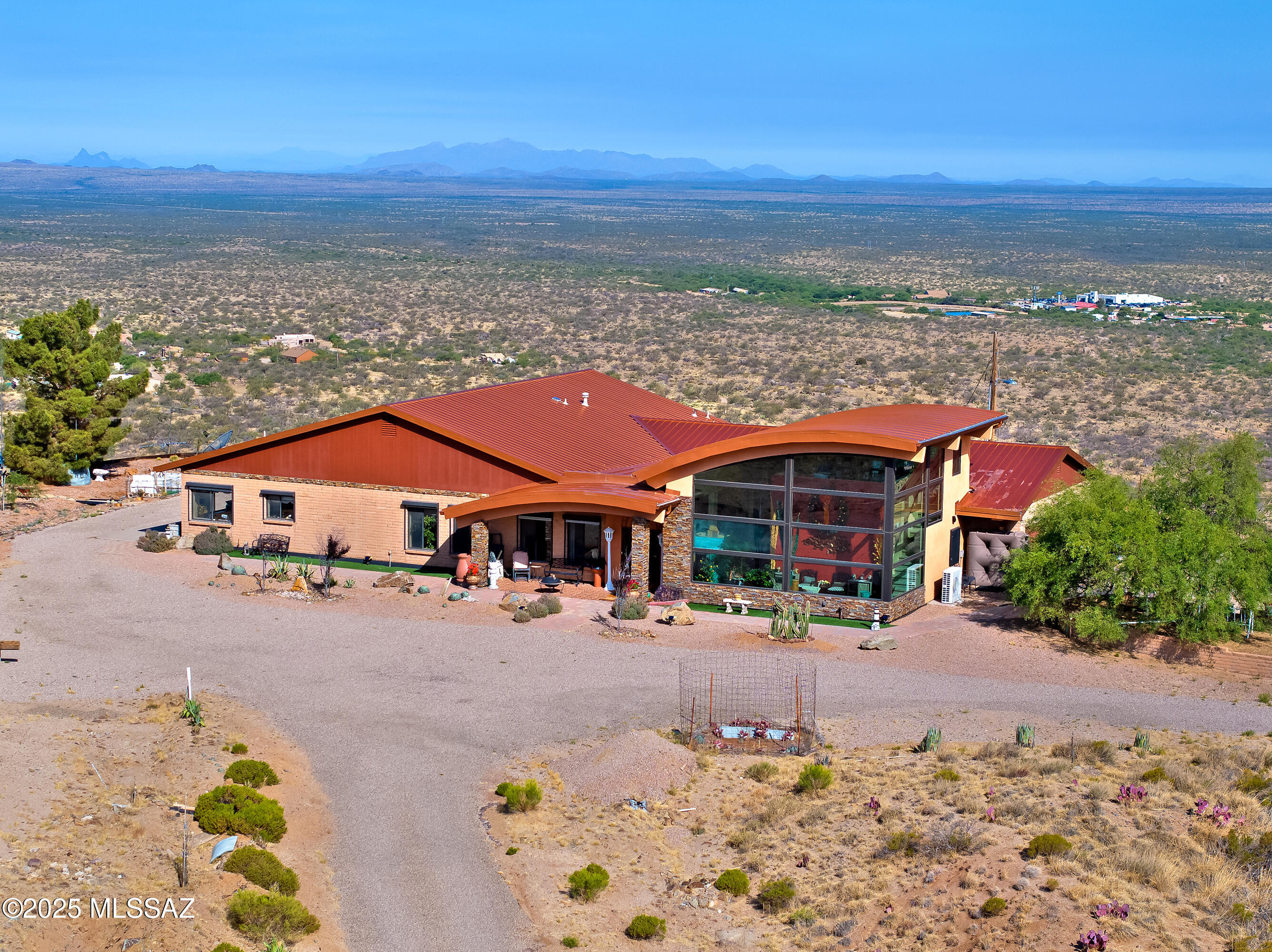 Discover elevated desert living at its finest in this custom 3,596 sq ft estate perched on 5.28 acres at one of Oracle's highest vantage points. Surrounded by extraordinary 360° mountain views and of multiple ranges, with a commanding perch that overlooks the entire town of Oracle.  This meticulously upgraded residence delivers rare privacy, refined finishes, and a layout designed for comfort, security, and versatility. 
The home features 4 bedrooms, 3 baths, and a flexible bonus space which could ideal for an office, fitness area, media space, or creative studio. the impressive 896 sq ft guest addition expands the living experience with floor-to-ceiling glass that frames sweeping natural scenery--perfect for visitors and multi-generational living at its best! The interior has been fully renovated with high-quality materials, updated cabinetry, upgraded counters, and modern flooring. Expansive windows bring in abundant daylight while capturing panoramic views from nearly every angle. A bright sunroom enhances the home year-round, naturally warming the living areas during cooler months and offering a comfortable space to enjoy the changing seasons.

Designed with security and longevity in mind, the property includes rolling window shutters, reinforced exterior doors, a standing seam metal roof, and a leaf-filter gutter system. These features create a worry-free lock-and-leave environment with exceptional durability.

Outside, a chip-seal driveway leads to your 8 garages one attached and two detached plus an attached greenhouse. The land offers mature fruit trees, wide-open space suitable for horses, and room for additional amenities, including an area usable as a helipad. A rainwater harvesting system with multiple collection barrels contributes to sustainable living and reduces reliance on municipal water.

This horse property combines elevated luxury, practical upgrades, and a setting that must be seen to be believed. From sunrise to sunset, every moment here is framed by unmatched scenery and peaceful desert beauty. This is a rare opportunity to own a true hilltop estate offering privacy, elevation and some of the most expansive views in the area,