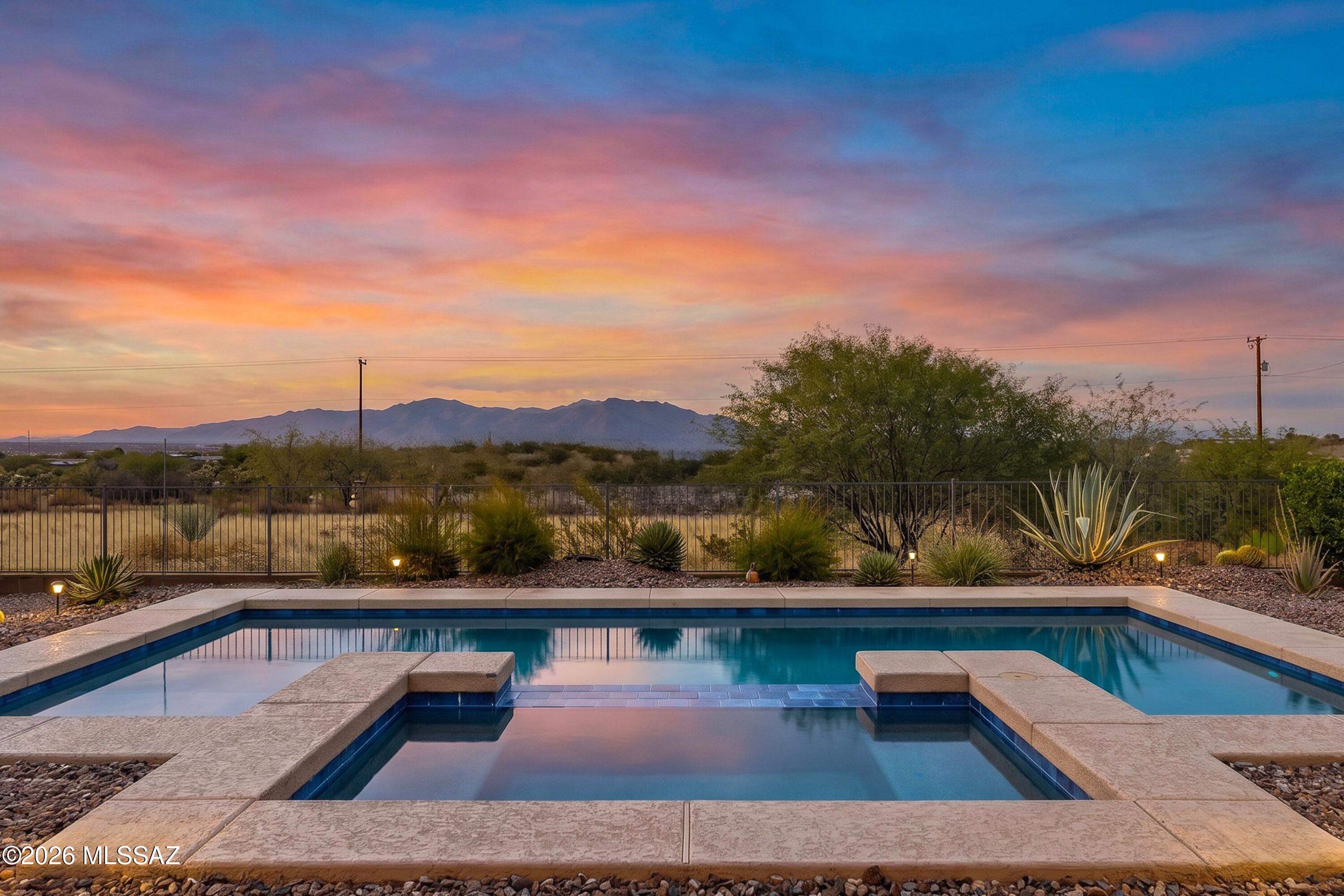 Welcome to an exceptional desert retreat behind the gates of Lazy K Bar Ranch, where panoramic mountain and Sonoran Desert views create a striking backdrop from the moment you enter. Spanning 2,443 square feet, this beautifully designed single-story residence offers three generously sized bedrooms, two-and-a-half bathrooms, and a versatile flex space ideal for a private office or den. Expansive windows fill the interior with natural light and showcase the views throughout. The open-concept living areas flow seamlessly into the chef-inspired kitchen, featuring granite countertops, abundant workspace, extensive cabinetry, and a spacious layout designed for everyday living and entertaining. The oversized primary suite offers a serene private retreat, complemented by a beautifully appointed bathroom with separate vanities and a spacious glass-enclosed walk-in shower. Two additional oversized bedrooms provide comfort and flexibility for family or guests. Outside, the saltwater pool and spa create an inviting retreat surrounded by sweeping desert, mountain, and sunset views. Whether entertaining beneath the covered patio, relaxing poolside, or unwinding in the spa, the outdoor setting offers privacy and tranquility. A two-car garage and separate one-car garage provide exceptional space for vehicles, storage, recreational equipment, or a workshop. Thoughtfully designed and beautifully positioned, this remarkable property offers refined desert living in one of Marana's most distinctive gated communities.