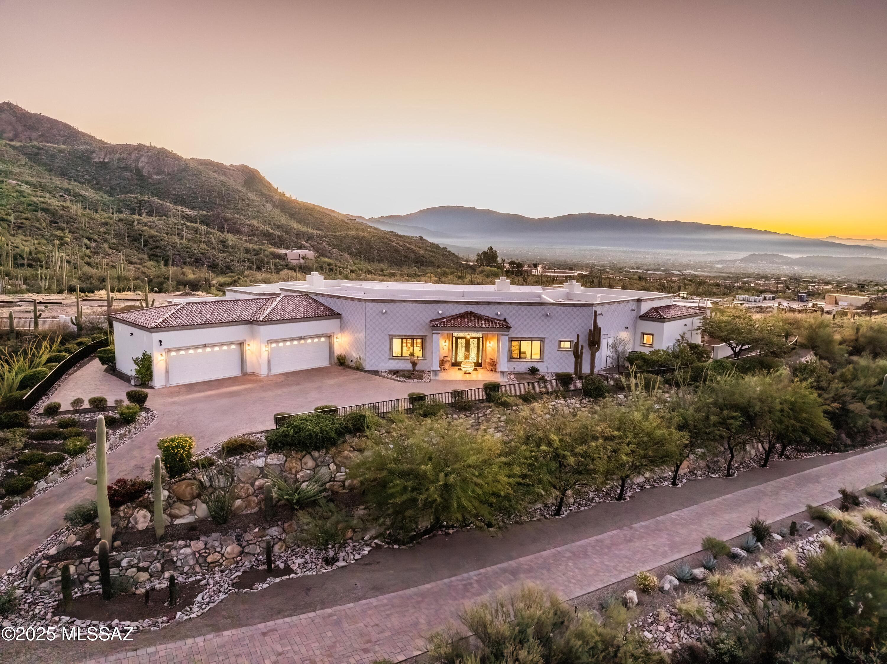 Perched at the crown of a quiet cul-de-sac in gated Finisterra, this hillside residence captures sweeping views of Ventana Canyon, the Catalina Mountains, and the city lights below. The architecture blends Mediterranean warmth with contemporary lines, creating a dramatic yet refined first impression the moment you step inside. Soaring ceilings, natural light, and thoughtfully crafted spaces guide you through a layout designed for both elevated living and effortless comfort. The primary suite feels like a private retreat, while the home's multiple living areas frame the surrounding landscape as if it were artwork. Outside, the setting truly takes over  a serene backdrop of mountains, sunsets, and open desert that turns everyday moments into something extraordinary.
