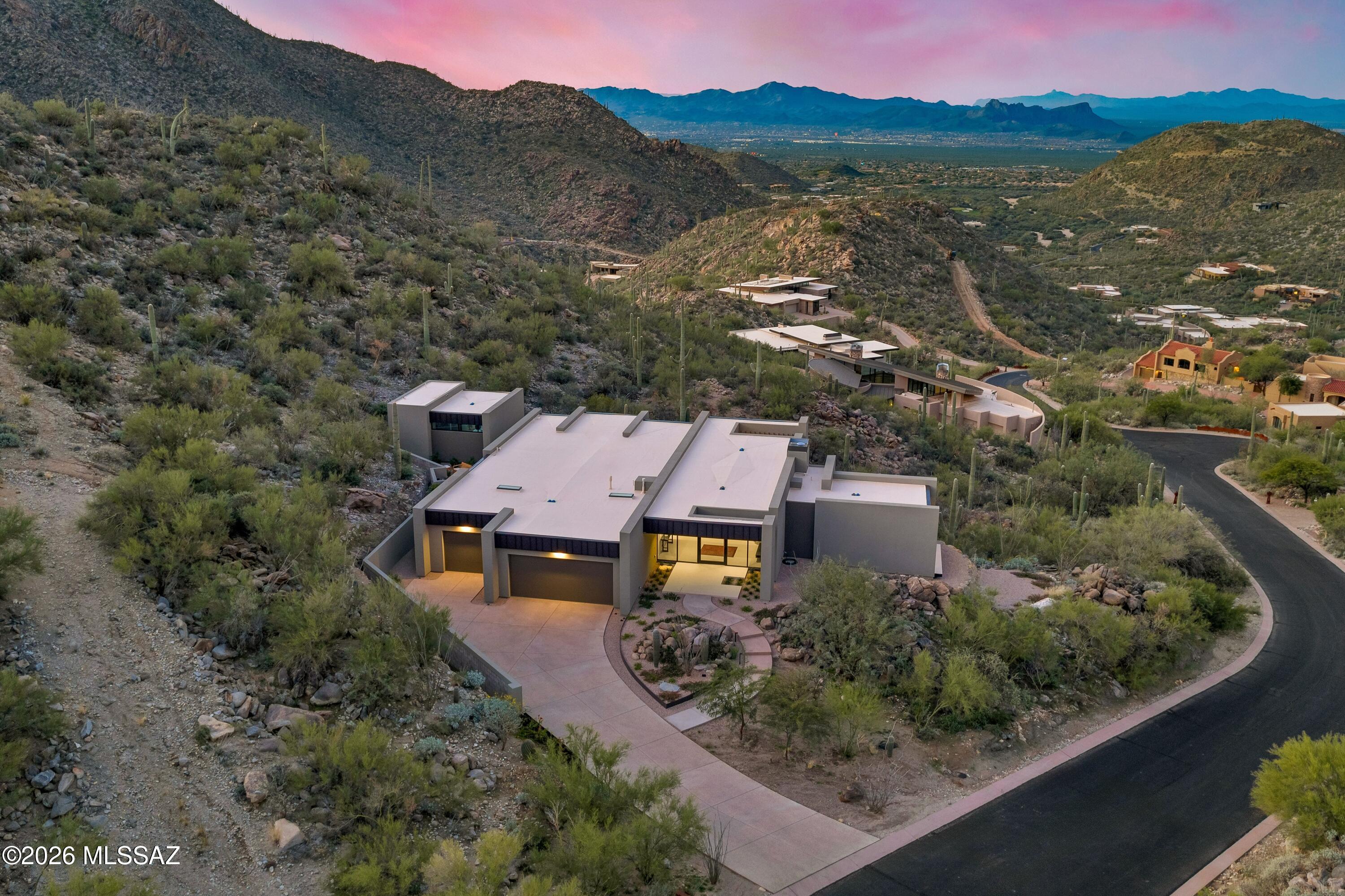 VIEWS FROM EVERY ROOM!! Completed in 2025, this brand-new residence was crafted from the ground up with thoughtful design and modern luxury at every turn. Perched on a premier hilltop homesite, the home was intentionally oriented to capture sweeping, unobstructed views from every room. Floor-to-ceiling windows wrap the entire residence, drawing the desert horizon, canyon walls, and ever-changing sky directly into the living spaces.
Designed by architect Serghei of SARI TERZI Designs, the home sits on a carefully selected lot within Dove Mountain's tranquil, gated Canyon Pass community--chosen specifically for its extraordinary vistas and natural serenity. The result is a rare blend of privacy, openness, and a seamless connection to the surrounding landscape. A striking rear façade of glass anchors the design, flooding the interior with natural light and framing the dramatic desert scenery. Expansive sliding glass doors open each room to its own private patio, creating effortless indoor-outdoor living and uninterrupted sightlines in every direction.  The property is presented as a three-bedroom home, featuring the primary suite and a versatile bedroom in the main house, complete with a generous full bath and closet. Inside, the home is elevated by custom, grain-matched walnut cabinetry by Summit Woodworking, thoughtfully integrated throughout the residence. The split floor plan places the primary suite on its own wing for maximum privacy, while the flexible bedroom sits opposite, ready to adapt to your lifestyle. For those dreaming of a pool, the generous lot offers ample space to design a custom outdoor oasis. The architect has even offered to create a personalized pool concept tailored to your vision and the home's breathtaking backdrop. This is a must-see -Call today for a showing!
