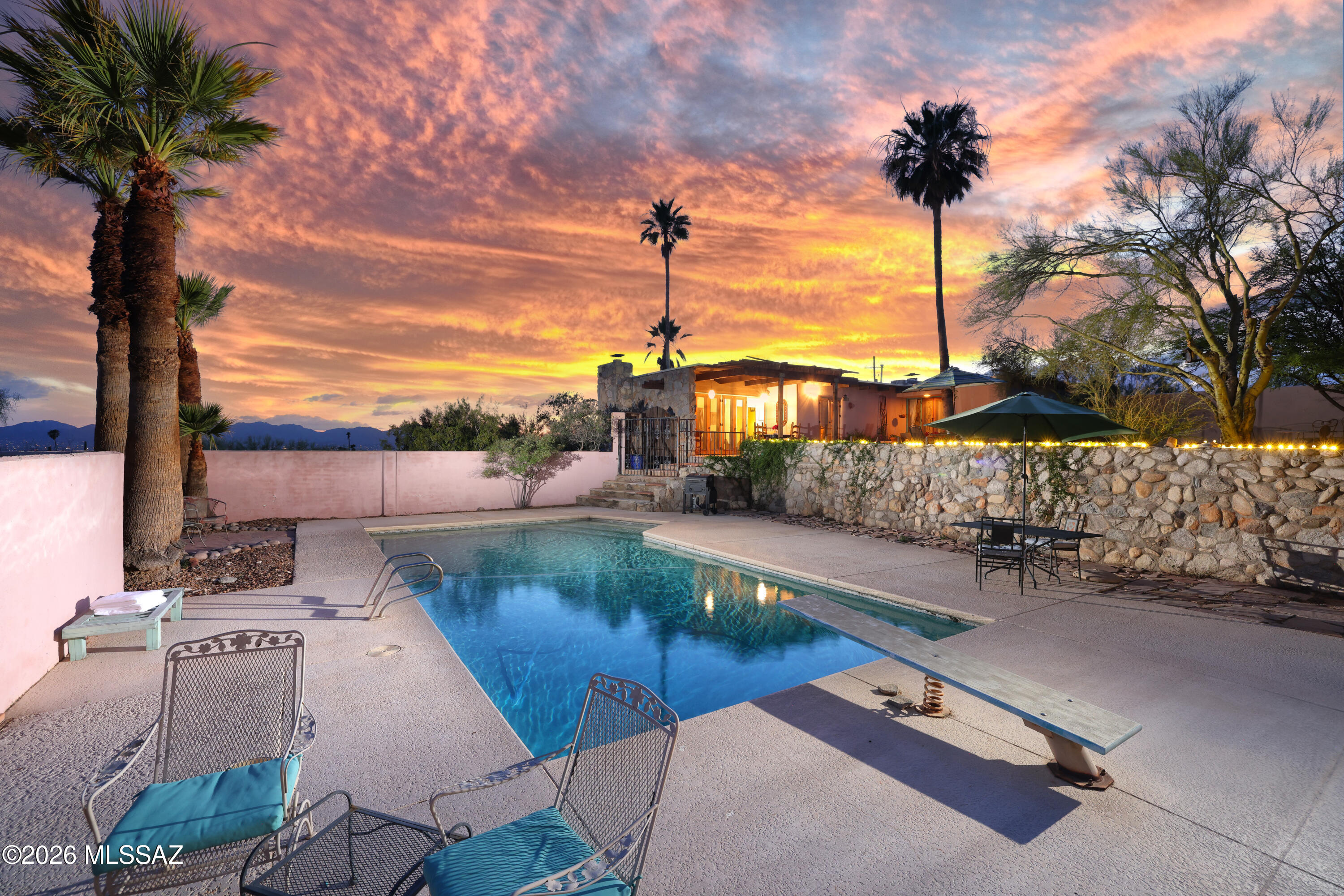 A rare opportunity to experience authentic mid-century modern design in the Tucson Foothills. Originally conceived in 1958 by noted architect Nicholas G Sakellar, this 3-bedroom, 2-bath residence embodies his purist modern expression--defined by intersecting planes, clean geometry, & a seamless relationship between structure & site.
Privately set on over three-quarters of an acre, the property captures sweeping panoramic views of the Catalina Mountains, Tucson Mountains, & A Mountain, along with sparkling city lights that emerge at dusk. Sakellar was known for his distinctive, architectural language featuring dramatic floor-to-ceiling narrow glass windows set into living area corners, blurring the boundary between interior & landscape. His thoughtful use of natural materials is evident .. throughout, with striking rock walls carried both inside and out, complemented by sculptural rock fireplaces that anchor the home's living areas.
The residence unfolds across three subtly separated levels, connected by short transitions that create spatial interest while maintaining an open, cohesive flow. Flagstone flooring extends throughout the living areas and continues seamlessly out to the covered patio, reinforcing the home's connection to the desert environment. From there, it flows through a wooden gate and gently down to the pool and inviting Kiva-style fireplace--creating a natural progression from interior living to outdoor retreat.
Outdoors, a resort-style pool creates a private setting framed by expansive desert and mountain vistas--an ideal environment for entertaining or enjoying Tucson's renowned sunsets.
The sellers have carefully maintained the home, ensuring its systems and functions remain in good working order while preserving its architectural integrity.
Ideally located near everyday conveniences and some of Tucson's most desirable destinations--including Whole Foods Market, Trader Joe's, and La Encantada with its collection of premier dining and shopping--this property offers the perfect balance of accessibility and seclusion, tucked away just far enough to provide a true sense of tranquility.
Over the course of his career, Sakellar produced an exceptional body of work, recognized not only for the quality and innovation of his designs, but also for the lasting influence he had on the many young architects who trained and worked alongside him. His contributions to the profession were honored with his elevation to Fellow of the American Institute of Architects (FAIA), one of the highest distinctions in architecture.
Faithful to its mid-century roots yet timeless in appeal, this residence offers a rare combination of architectural pedigree, natural beauty, and livable comfort--an exceptional opportunity for those who value design, history, and the Tucson lifestyle. Be sure to visit Pima Canyon Trailhead just 15 minutes away by foot from the home with 45 parking spots for your convenience.