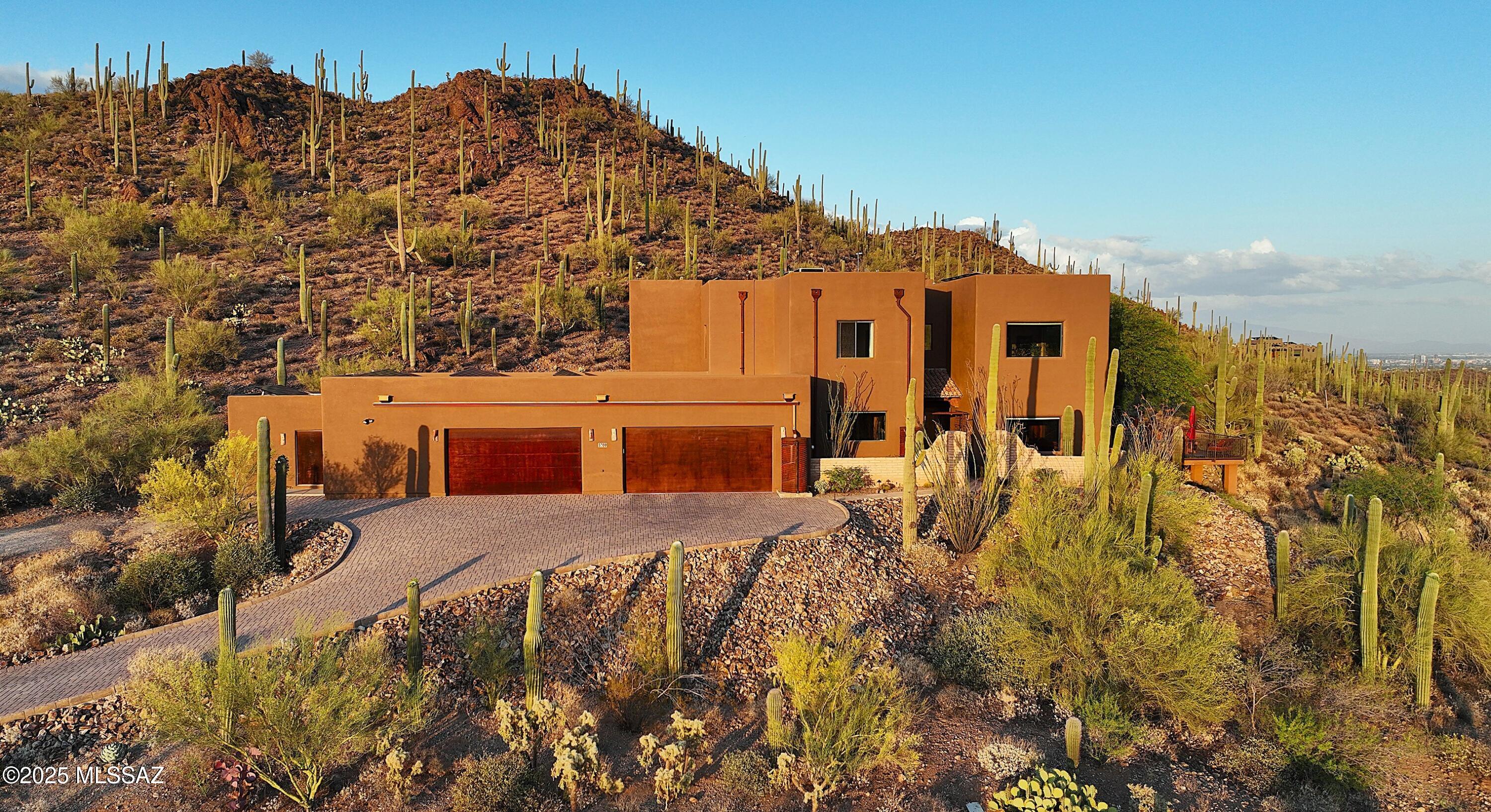 Spectacular unobstructed views from every window of this luxury custom home on a quiet 3.31 ac saguaro-studded hillside lot. Built w/ energy-efficient ICF construction & powered by owned solar: $0 elec bill 2025. Interior highlights include imported hand-crafted Alamo cabinetry & doors, chef's kitchen & climate-controlled dbl-door wine cellar. Many upgrades throughout.1500 sq ft oversized 4-car garage w/ finished floors, mini-split & views for gym, workshop or hangout. Bonus 300 sq ft storage room. Entertain or unwind on the scenic deck, 2 patios or upstairs balcony w/ sweeping mountain & city light views. Peace & luxury under the stars. Walk to Sweetwater Preserve Trails. Gated community. No HOA. Great rental income opportunity or full time residence.  Minutes to I-10 & downtown.