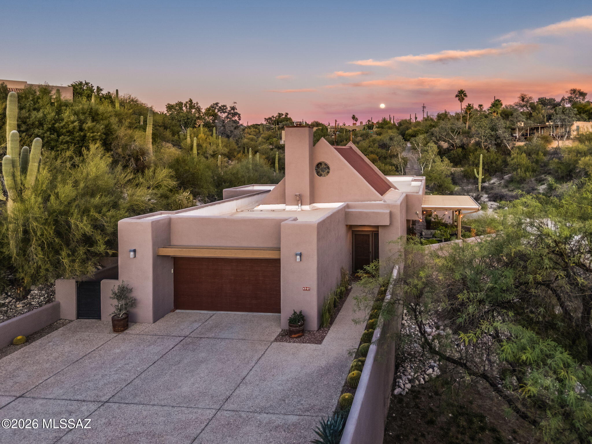 Perched on a ridgetop within a private enclave of four homes, this truly special SW contemporary by David Tyson captures breathtaking city lights, mountain, and sunset views. Soaring plank and beamed ceilings define the dramatic great room with gas fireplace and walls of windows. The gourmet kitchen features stainless appliances custom cabinetry and a striking soapstone  island designed for gathering. The primary suite is a true retreat with its own fireplace and patio access. Extensive upgrades include new HVAC, ,fresh interior/exterior paint, Saltillo bedroom floors, rebuilt pergola, enhanced BBQ area new hall bath shower, reimagined yard with improved access and a professionally installed retaining wall for lasting stability. An exceptional blend of design, location and livability.