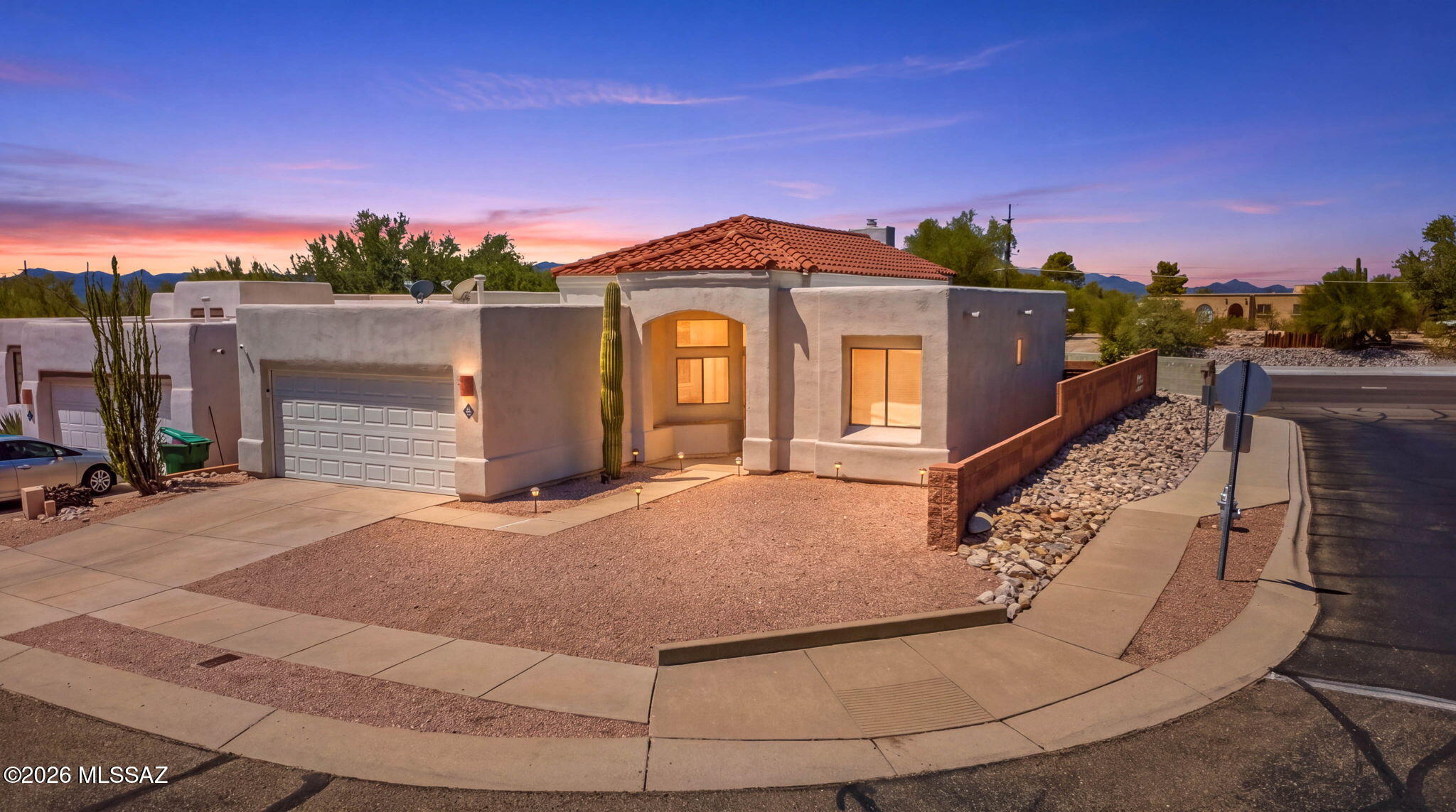 Stylish Santa Fe Retreat with Resort-Style Backyard in North Tucson

Welcome to 1352 W Hopbush Way, a beautifully updated 3-bedroom, 2-bathroom home offering 1,415 square feet in one of North Tucson's established 85704 neighborhoods. With classic Southwestern architecture -- a tiled roof, arched entry, and desert landscaping accented by a statement saguaro -- this home makes a striking first impression, especially as dusk settles over the mountain views beyond.

Step through the rustic wood and iron front door into a bright, vaulted great room anchored by a sleek linear gas fireplace with a floating wood mantel and mounted TV. Tile flooring flows throughout the main living areas, and oversized clerestory windows fill the space with natural light.

The fully remodeled kitchen is a tru showpiece: crisp white shaker cabinetry with gold hardware, quartz waterfall-edge countertops, a farmhouse sink, a gold pot-filler over the gas range, a penny-tile backsplash, built-in beverage fridge, and a large island with bar seating -- perfect for entertaining or everyday living.

The primary suite offers a spacious layout with a walk-in closet and an en-suite bath featuring a dual-sink vanity with quartz counters, a step-in shower, and a large mirrored medicine cabinet.

Out back, discover a true entertainer's dream: a covered patio topped with a corrugated pergola roof and market lights, a built-in stone bar with seating, a lounge area, and space for a grill and dining table -- all overlooking a low-maintenance turf lawn framed by block-wall fencing for privacy.

Additional features include a 2-car garage, updated fixtures throughout, and a location close to shopping, dining, and top-rated Amphitheater schools.

This move-in-ready home blends modern updates with timeless Southwestern charm -- schedule your showing today!