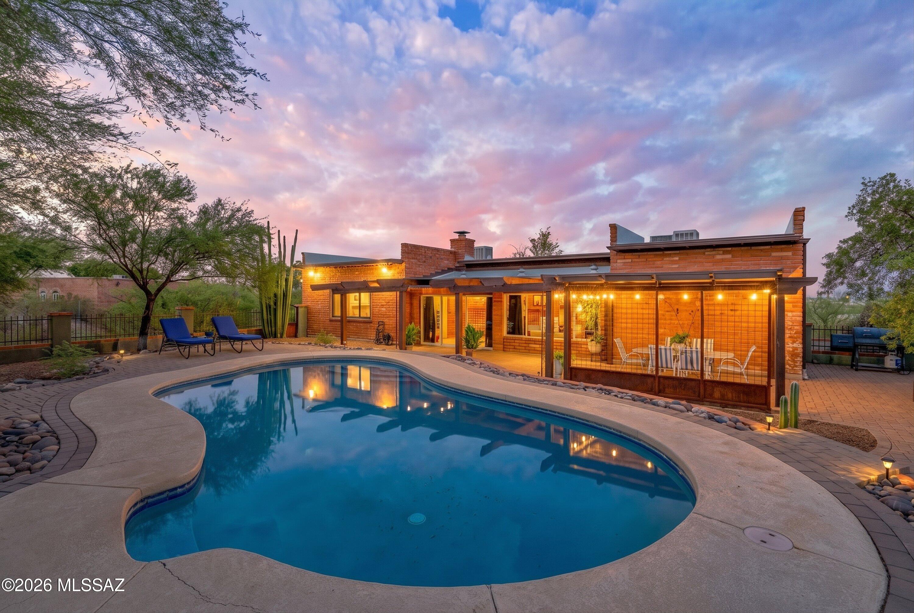 Experience the perfect blend of Southwest charm, privacy, and convenience in this beautiful 4-bedroom, 2-bath adobe block home on Tucson's highly desirable Westside. Situated on a spacious .78-acre lot with no HOA, this 2,520-square-foot residence offers breathtaking mountain views, colorful sunsets, abundant wildlife, and the peaceful feeling of rural living, just minutes from everyday conveniences.
A gorgeous courtyard welcomes you into an open great room filled with natural light, beautiful windows, and a cozy wood-burning fireplace. At the heart of the home, the spacious kitchen features custom cherry cabinetry, granite countertops, and a large center island offering generous workspace, storage, and seating for casual dining or entertaining. The thoughtfully designed split floor plan provides comfort and privacy, while the expansive Arizona room creates additional space for relaxing, gathering, or enjoying Tucson's year-round sunshine. The generously sized primary suite features a walk-in closet and a spacious bathroom with a Jacuzzi tub and separate shower. Outside, your private desert retreat awaits with a sparkling swimming pool, mature shade trees, a covered patio, and plenty of space to gather, garden, or simply take in the surrounding mountain scenery. A detached shed and workshop provide valuable storage and workspace, while the oversized lot offers room for an RV, recreational toys, trailers, and more. Conveniently located near grocery stores, restaurants, Interstate 10, Downtown Tucson, hospitals, and Tucson International Airport, this special property delivers the best of Southwest living; space, serenity, spectacular views, and easy access to the city. A must see!