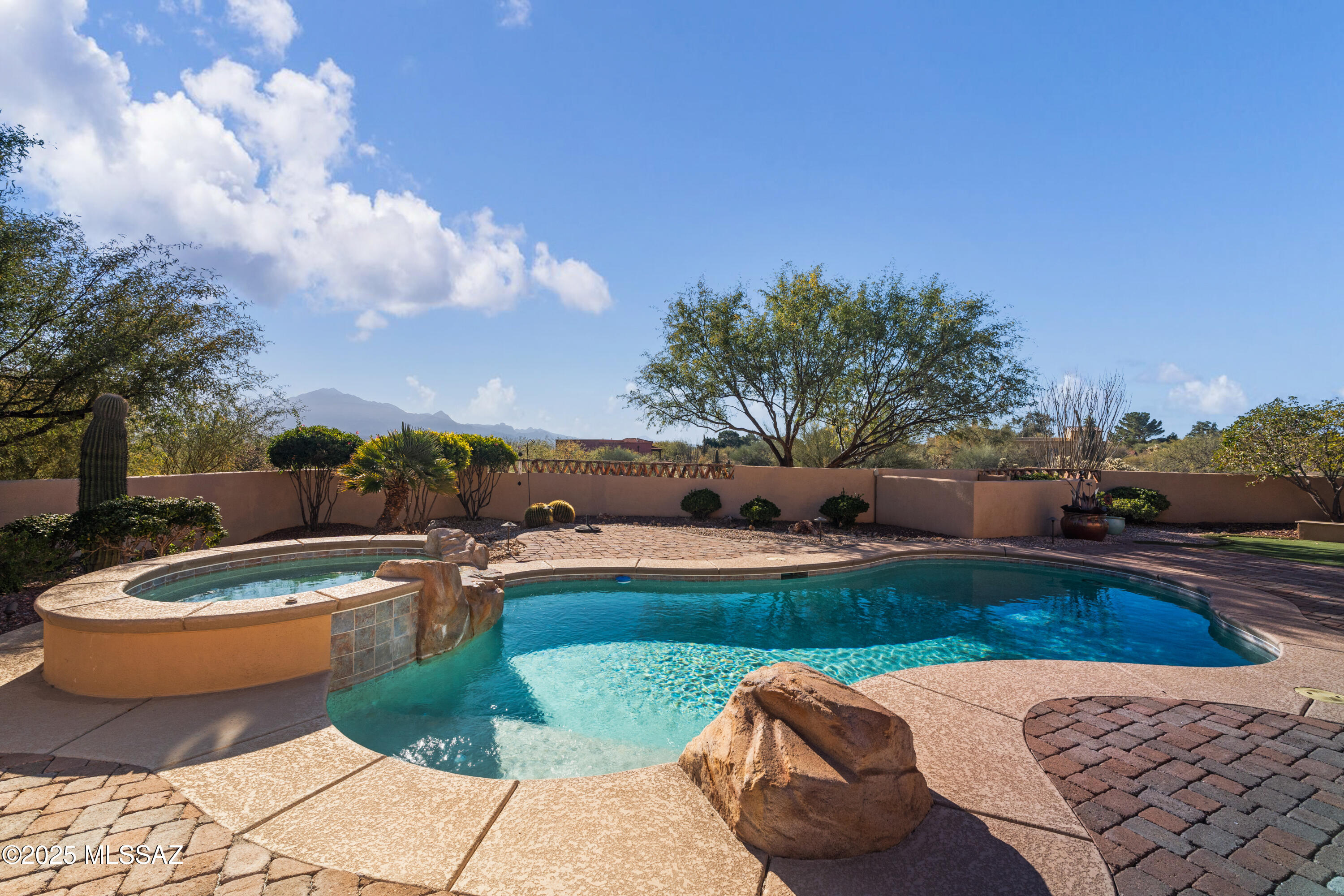 Exquisite gated Santa Barbara Ranch-style estate showcasing the pinnacle of Southwest elegance with unobstructed, panoramic views of the Santa Rita Mountains. Every detail of this home reflects thoughtful design, luxurious craftsmanship, and the seamless integration of indoor and outdoor living, offering a rare lifestyle of privacy, serenity, and refined entertaining.

Enter through a tranquil courtyard featuring a classic fountain and Southwest-tiled gas fireplace, connecting gracefully to the foyer, office/den, primary suite, and guest accommodations. The courtyard sets the tone for the home's signature indoor/outdoor flow, inviting natural light and sweeping mountain vistas throughout the main living spaces.

The gourmet kitchen is a chef's dream, featuring a Wolf six-burner gas stove, Sub-Zero refrigerator, expansive island with breakfast bar, and premium custom cabinetry. A wet bar with ice maker and wine cooler elevates entertaining, while a formal dining area adjacent to the kitchen and great room provides an elegant setting for intimate dinners or grand gatherings. The adjoining family/media room boasts state-of-the-art audiovisual systems, offering a cinematic experience for movie nights and sporting events.

A private courtyard casita offers luxurious guest accommodations with a Murphy bed, walk-in closet, full bath with tub and shower, and a dedicated mini-split system. The main residence also features an additional guest bedroom with ensuite bath and walk-in closet, and a spacious office/den with built-in desk, French doors, and direct courtyard accessperfect for work, study, or quiet retreat. Designer paint, 8-foot doors, plush carpeting in bedrooms and office/den, and plantation shutters throughout (solar screens in primary and den) highlight the home's exquisite finishes.

The primary suite is a private sanctuary with direct pool access, mountain views, and a spa-inspired bath featuring dual vanities, a makeup area, garden tub, walk-in shower, and separate water closet.

The resort-style backyard is a desert oasis designed for relaxation and entertaining. A chlorine pool has a brand new heater with electic controls and also has directly-plumbed solar heat, spa, putting green, and fully equipped outdoor kitchen with gas BBQ, bar seating, and new exterior refrigerator provide the ultimate setting for alfresco living. Architectural details include brick pavers, flagstone stepping stones, saguaro accents, and lemon, pink grapefruit, and orange trees, complemented by a walk-up balcony offering sweeping mountain and backyard views.

Additional highlights include security doors on all exterior entries, a 3-car garage with epoxy floors, cabinetry, high storage, workbench, and man door providing direct access to the backyard, and a laundry room with sink conveniently located off the garage entry. Advanced systems include EZ Water, Pentair REV reverse osmosis, and dual-zoned HVAC.

This rare gated estate masterfully blends luxurious finishes, thoughtful design, and resort-style outdoor living with breathtaking desert and mountain vistasa true Southwest masterpiece for those who demand elegance, privacy, and unparalleled comfort.

Every corner of this home is designed for comfort, elegance, and enjoymenttruly a place you will love coming home to every day.