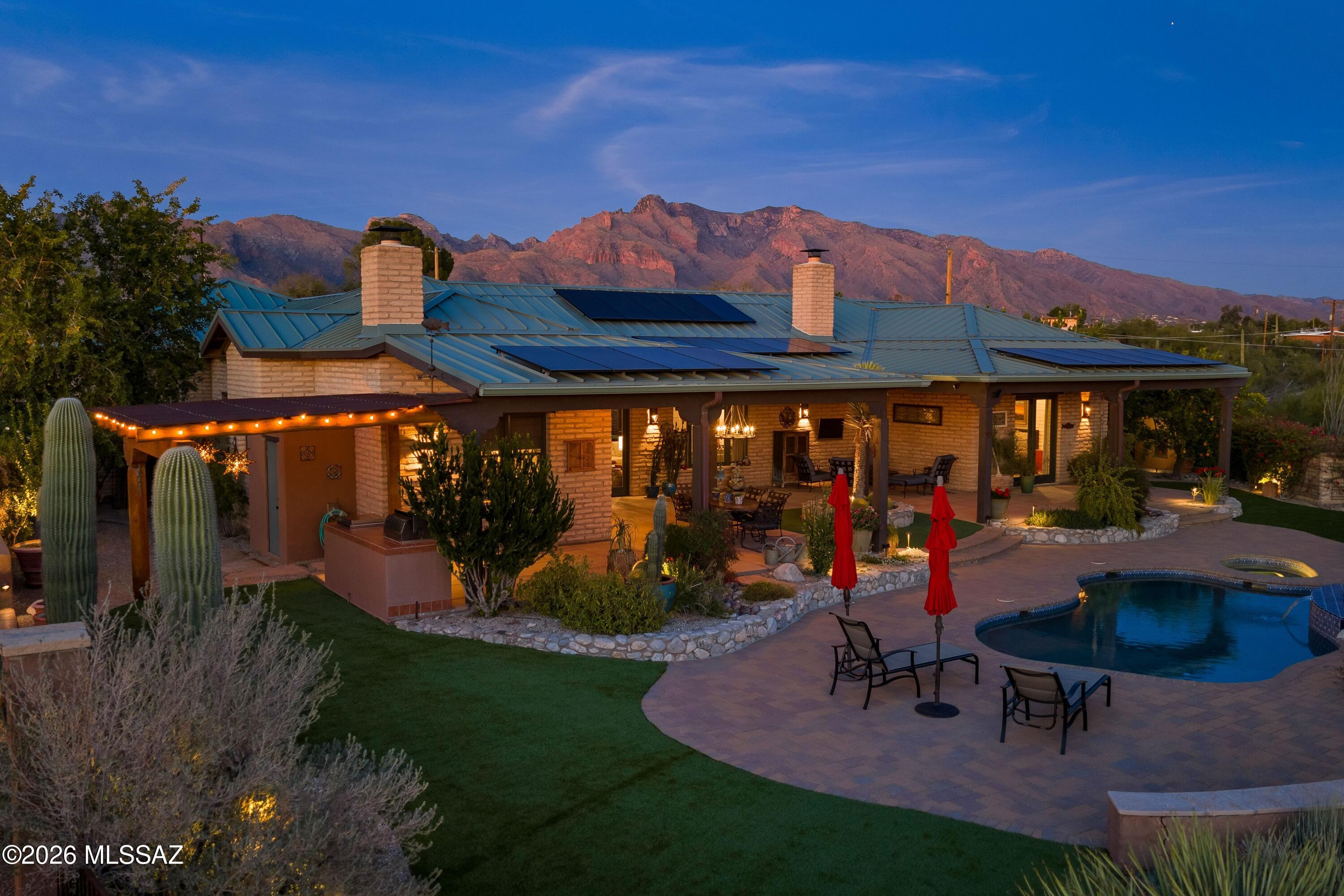 Set on 3.41 acres of pristine Sonoran Desert hillside, this exceptional cement-stabilized mud-adobe estate offers sweeping city lights, mountain, and sunset views with timeless Southwestern architecture and modern luxury throughout. The 3-bedroom, 3-bath main residence is complemented by a private 1-bedroom, 1-bath guest casita with full kitchen—ideal for guests, multigenerational living, or a private studio.Built in 2007, the main home showcases exposed wood beam ceilings, painted interior adobe brick walls, polished concrete floors, 8' alder doors, custom wood columns, and two authentic beehive fireplaces with designer tile accents. A warm, cohesive palette blends natural wood, earth tones, and soft plaster finishes. Thoughtful upgrades include custom Roman shades, an office with built-in cabinetry, a spacious laundry with extra refrigeration, tankless gas water heaters, whole-house water softener, interior/exterior fire sprinklers, and zoned Trane HVAC with gas heat (replaced 2023).
The chef's kitchen was fully renovated in 2024 by acclaimed Tucson designer Marina Luz of LCM Interiors and features custom walnut cabinetry, honed quartzite countertops, designer tile backsplash, plastered range hood, oversized 9' island, walk-in pantry, Sub-Zero refrigeration, Wolf 6-burner gas range, built-in Thermador oven and microwave, wine refrigerator, and built-in ice maker. The kitchen opens seamlessly to dining and living areas anchored by the second fireplace.
The detached guest casita (approx. 800 sq ft, built 2013) offers complete privacy with its own driveway and one-car garage. It includes an open living/dining area, full kitchen, polished concrete floors, recessed lighting, ceiling fan, laundry, storage, and a private outdoor shower enclosed by stucco walls with city views.

Outdoor living is equally impressive with covered patios, wood beam detailing, a cantera stone fountain courtyard entry, outdoor beehive fireplace, stainless steel BBQ, synthetic turf installed 1/2026, and resort-style pool re-plastered in 2023 with new tile and warranty. Additional highlights include owned solar (44 panels) with upgraded 400 AMP service, raised-seam metal roof, gated entry, paver driveway, mature citrus, low-care irrigation, twilight landscape lighting, Ring cameras, oversized 3-car garage at the main house plus casita garage, and select furnishings available via separate bill of sale.
A rare offering blending authentic adobe craftsmanship, privacy, views, and refined desert living.
