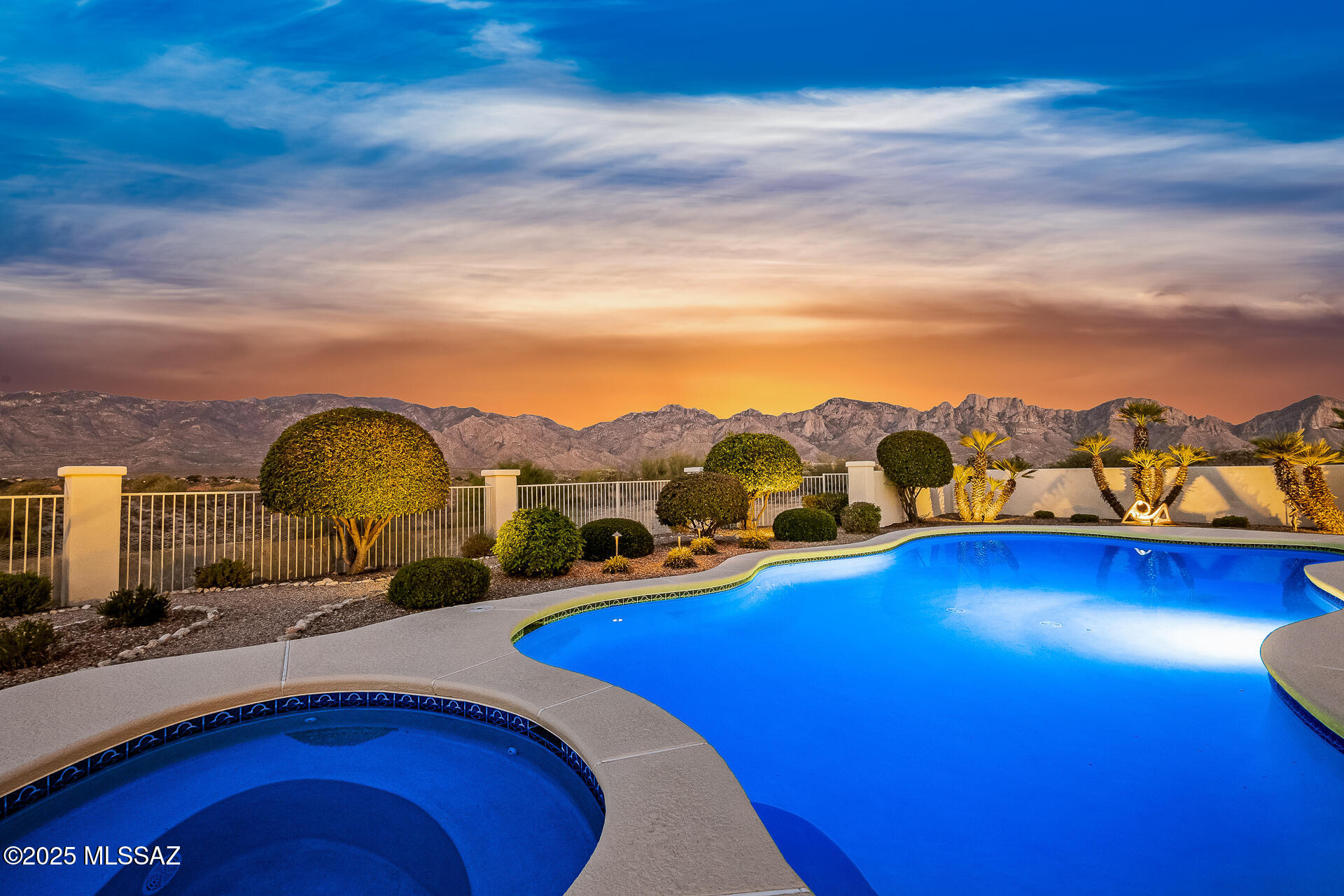 Situated at the end of a quiet cul-de-sac in the gated enclave of High Mesa, this exquisite 3,580SF single-story estate blends timeless Mediterranean architecture with refined modern comforts, European flair and sweeping panoramic Catalina Mountain views. Thoughtfully designed and impeccably maintained, this 4BR/3BA residence with a spacious den/office offers exceptional livability ideal for both intimate gatherings and grand-scale entertaining. From the moment you arrive, the home's curb appeal captivates with meticulously maintained mature desert landscaping, brick paver driveway and charming gated courtyard reminiscent of a European villa. Inside, you're greeted with old-world craftsmanship and modern elegance with travertine tile and bamboo wood flooring, soaring vaulted ceilings, arched doorways and rich architectural detailing evoking a sense of classic European sophistication.
The open-concept kitchen and family room form the heart of the home, featuring granite counters and backsplash, stainless appliances, built-in cabinetry, and a dry bar with beverage and wine cooler. The split-bedroom layout ensures comfort and privacy. The primary suite is a peaceful retreat featuring an electric fireplace, dual walk-in closets, newer walk-in shower, a newer Duravit soaking tub, newer bidet and toilet, and direct patio access. Every space has been thoughtfully upgraded, with newer toilets in all bathrooms, surround sound throughout the home and patio, modern lighting and no interior steps for effortless living. Additional systems include a newer HVAC, tankless water heater, central vacuum & Rolling Shutters. The resort-caliber backyard is designed for year-round enjoyment. A sparkling pool and spa are surrounded by Kool decking and flagstone, complemented by a built-in BBQ and griddle, multiple seating areas, and newer pool equipment all set against a breathtaking backdrop of mountain views. Whether you're sipping espresso under the covered patio or dining al fresco under the stars, this outdoor setting evokes the relaxed elegance of a European countryside estate. The garage is equally impressive with Polyurea-coated floors and storage cabinets. Perfectly located in the heart of Oro Valley near Honey Bee Canyon Park, scenic trails, and the exclusive Stone Canyon Club, this home is just minutes from Catalina State Park, The Loop trail system, and the shops, dining, and entertainment of Oro Valley Marketplace.