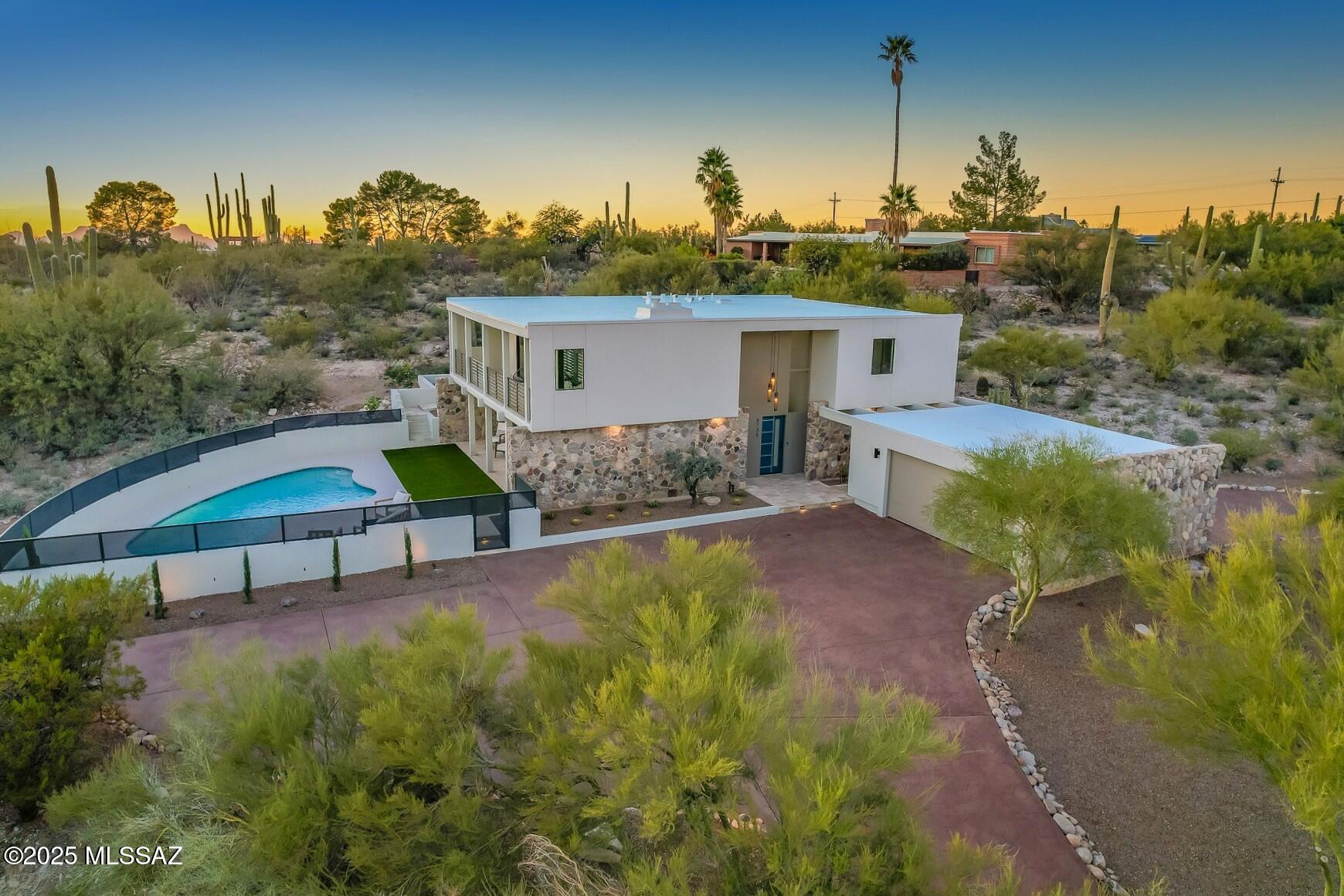 Step into iconic Desert Modernism in this exquisitely renovated Mid-Century residence nestled in the Foothills of Tucson. Evoking Palm Springs circa 1960, the home celebrates clean architectural lines, expansive walls of glass & seamless connection to the surrounding desert landscape. Dramatic floor-to-ceiling windows frame sweeping city lights & mountain vistas, while rugged natural rock walls provide striking architectural accents. Seamless Indoor-Outdoor living w/ North/South facing Patios & stunning city lights from Primary Suite, Den & View Deck. Comprehensive renovation honors the home's mid-century soul while upgrading it for modern living. All New: Roof Coat, HVAC, Windows, Doors, Floors, Kitchen, Bathrooms, Stucco, Landscape Lighting, Fixtures, Upgraded Gas & Electrical Service +