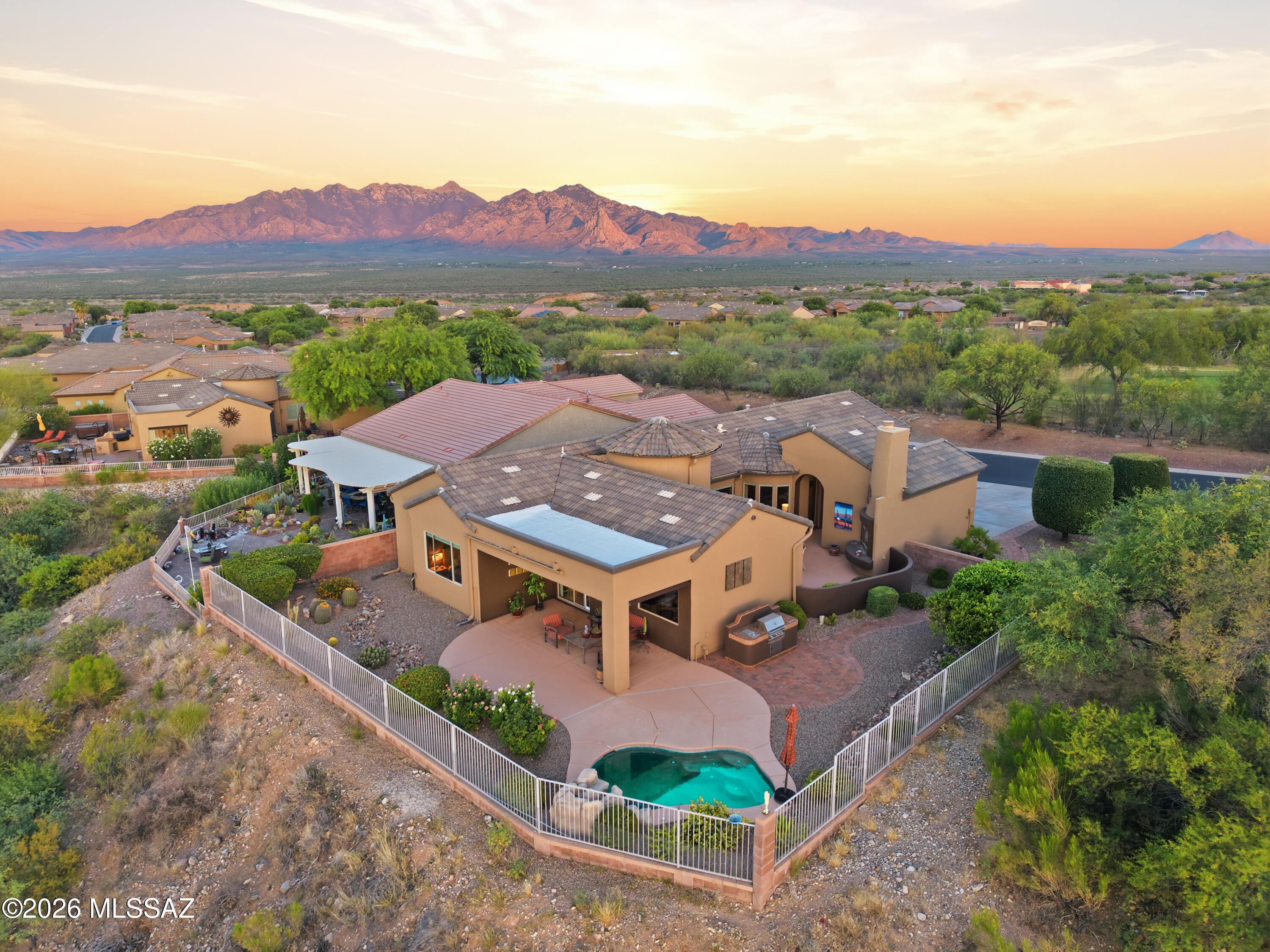 Discover desert living in the prestigious Canoa Ranch community, perfectly positioned along the Canoa Ranch Golf Course with sweeping mountain views, lush fairways, and unforgettable sunrises and sunsets. This home offers a rare blend of sophistication, comfort, and in indoor-outdoor lifestyle Southern Arizona buyers love. A private gated courtyard welcomes you to a spacious sitting area and a cozy gas fireplace creating an inviting space to relax or entertain. Multiple access points from inside the home make this courtyard feel like and extension of the living space. Inside, warm earth-tone colors, vaulted ceilings, and a flowing floorplan set a serene tone. Unique indoor planter walls add architectural interest while maintaining visibility throughout the main living areas. The kitchen is appointed with ample cabinetry, stainless steel appliances, granite countertops, a central island with seating, and a charming breakfast nook. Tile flooring flows through the main living spaces, with soft carpet in the bedrooms for added comfort. The primary suite is roomy, featuring a large window framing the backyard and mountain views. The primary bath includes dual vanities, shower, soaking tub and a large walk-in closet. The split bedroom plan ensures privacy for guests and guest bath has shower/tub combination. A versatile office/den provides the perfect space for work or hobbies and includes direct access to the courtyard. The living room is bright and inviting with sliders opening to both the courtyard and the back patio. Solar screens enhance comfort while preserving the view. Step outside to the backyard designed for true enjoyment- lush landscaping, rose bushes, fruit trees, a sparkling spool, and a built-in grill make outdoor dining and barbeques effortless. Practical upgrades add peace of mind, including a 3-car garage with 2 utility sinks and storage cabinets, newer HVAC, exterior paint completed aprox. 2 years ago, and a 2022 water heater. This home is a stand-out opportunity in Canoa Ranch.