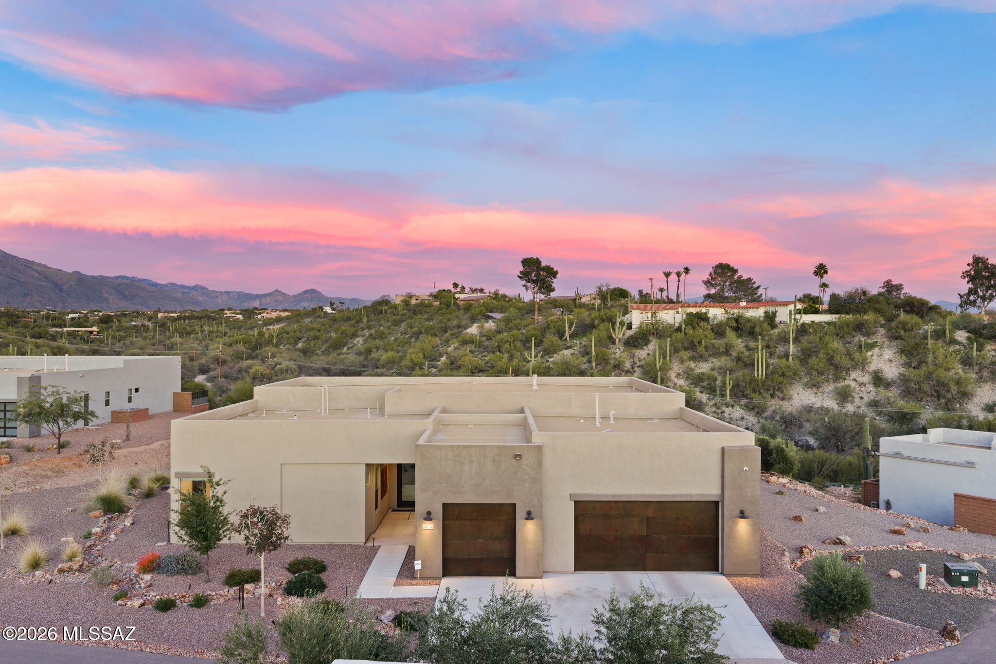 This newly built in 2024, exquisite, modern, custom-built residence offers an unparalleled blend of sophisticated contemporary design and luxurious desert living in the heart of the Arizona foothills. Spanning 3,302 square feet, this 4-bedroom + office, 4.5-bathroom masterpiece situated on 1.11 acres in the highly desired Catalina Foothills, showcases thoughtful upgrades and high-end finishes throughout, creating a seamless flow between indoor elegance and breathtaking outdoor vistas.  Step through the sophisticated glass pivot door to an open-concept great room bathed in natural light from expansive floor-to-ceiling glass sliders and windows that frame panoramic mountain views. The gourmet kitchen is a chef's dream, featuring premium quartz countertops, custom cabinetry, top-tier LG appliances, a drop ceiling over the island with accent lighting, and a spacious island perfect for entertaining. Porcelain tile flooring flows effortlessly throughout the home, complemented by elegant porcelain tile accents in the bathrooms and covered patio areas.  The primary suite is a serene retreat with a spa-inspired master bath boasting quartz countertops, modern fixtures, and abundant natural light. Additional bedrooms provide generous space and privacy, each with an ensuite.  Outdoor living reaches resort-level appeal with an expansive covered patio, integrated seating areas, thoughtful hardscaping, and a captivating outdoor gas firepit that serves as the perfect centerpiece for evening gatherings. Harmonizing with the surrounding desert landscape, enjoy El fresco dining under string lights, cozy fireside relaxation as the sun paints the Catalina mountains, or simply unwind in the thoughtfully designed spaces that blur the line between indoors and out.  Additional conveniences include a state-of-the-art security system with video surveillance and alarm, mesh WiFi system for seamless connectivity, and two nearly new Samsung Neo QLED 4K Smart TVs (75" in the living room and 65" in the back bedroom) paired with a Sonos sound bar, which convey with the property. The home's modern architecture, premium materials, and meticulous attention to detail make it an ideal sanctuary for those seeking privacy, luxury, and effortless Arizona living.
 
Don't miss this rare opportunity to own a turnkey modern gem in one of the most desirable foothill locations. Schedule your private showing today!
