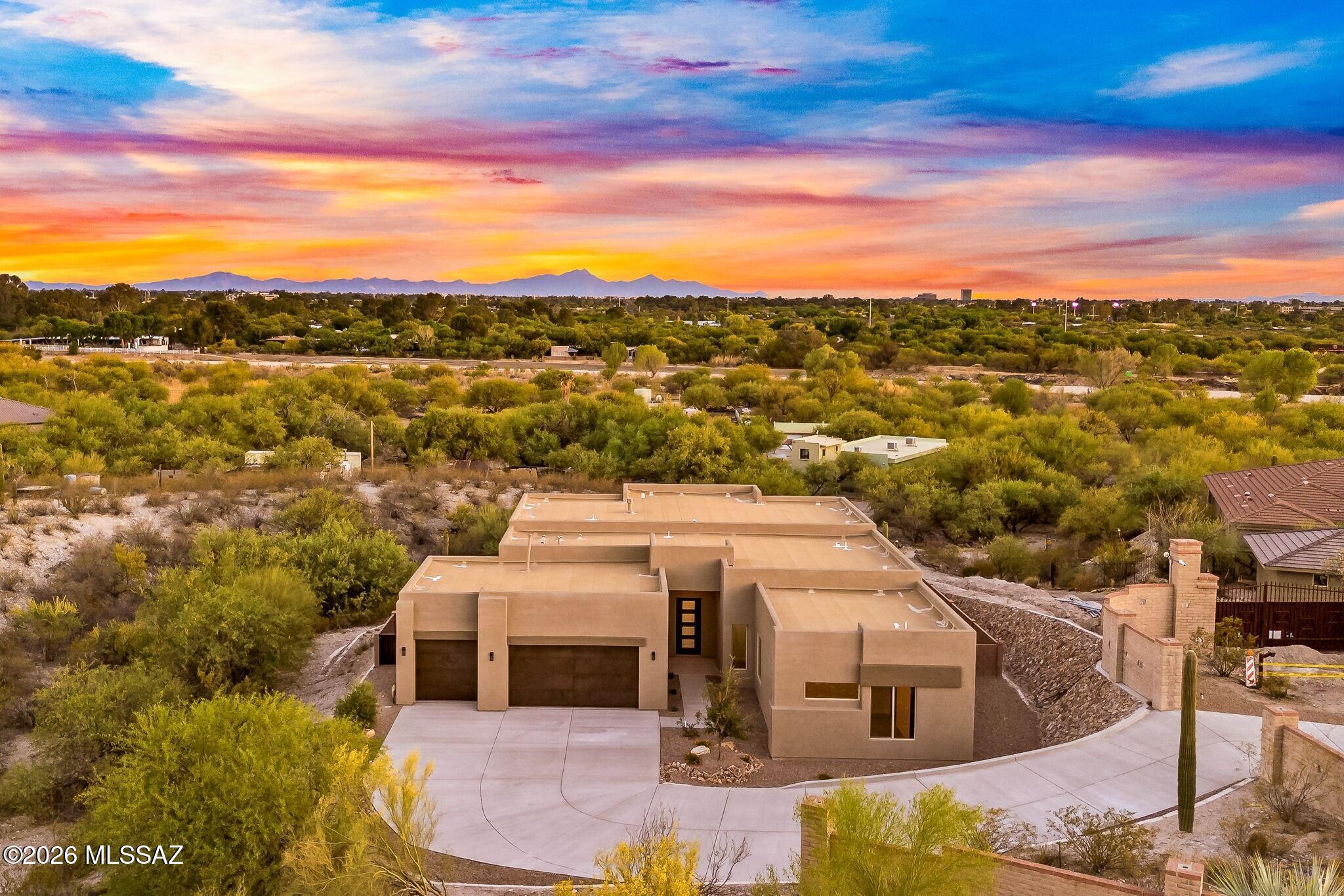 Experience refined desert living in this rare, newly built residence by Fairfield Homes, featuring the coveted Acacia floor plan. Tucked within the prestigious Catalina Foothills, this home offers a seamless blend of architectural elegance, modern comfort, and natural beauty.
Upon entering, you're welcomed by soaring 12-foot ceilings and a dramatic open layout designed to impress. A 16-by-10-foot multi-panel sliding glass door draws your eye outward to the covered patio, effortlessly merging indoor and outdoor living and inviting you to take full advantage of Tucson's year-round sunshine.
The expansive great room centers around a sleek modern gas fireplace and flows directly into the chef's kitchen and dining area. Designed for both daily living and entertaining, the kitchen features a striking quartz island, premium stainless steel appliances, a stylish tile backsplash, and an oversized walk-in pantry for abundant storage.
The private primary suite is a serene escape, enhanced by 8-foot interior doors that add volume and elegance. The spa-inspired bath includes a fully tiled walk-in shower, an oversized custom closet, and exquisite designer fixtures. Two guest ensuites, each with their own private baths and walk-in closets, provide a welcoming and luxurious experience for family or visitors. A flexible bonus room sits between them--ideal for a den, teen room, office, or creative studio.
Every detail throughout the home has been carefully considered, from the thoughtfully curated tile flooring to the refined designer finishes. Expansive windows frame captivating views of the Catalina Mountains or the surrounding Sonoran desert from nearly every room.
The backyard is fully landscaped with low-maintenance artificial turf and features a built-in fire pit--perfect for relaxed evenings or entertaining under the stars. From this vantage point, enjoy a view of the private bosque of trees below and even take in Tucson Country Club's fireworks displays from the comfort of your own yard.
A spacious three-car garage completes the package, while the prime location places you just moments from the scenic Rillito River Walk, Whole Foods Market, upscale dining, and highly rated schools including Basis and The Gregory School. This exceptional home offers the perfect balance of tranquility, sophistication, and convenience in one of Tucson's most desirable neighborhoods.