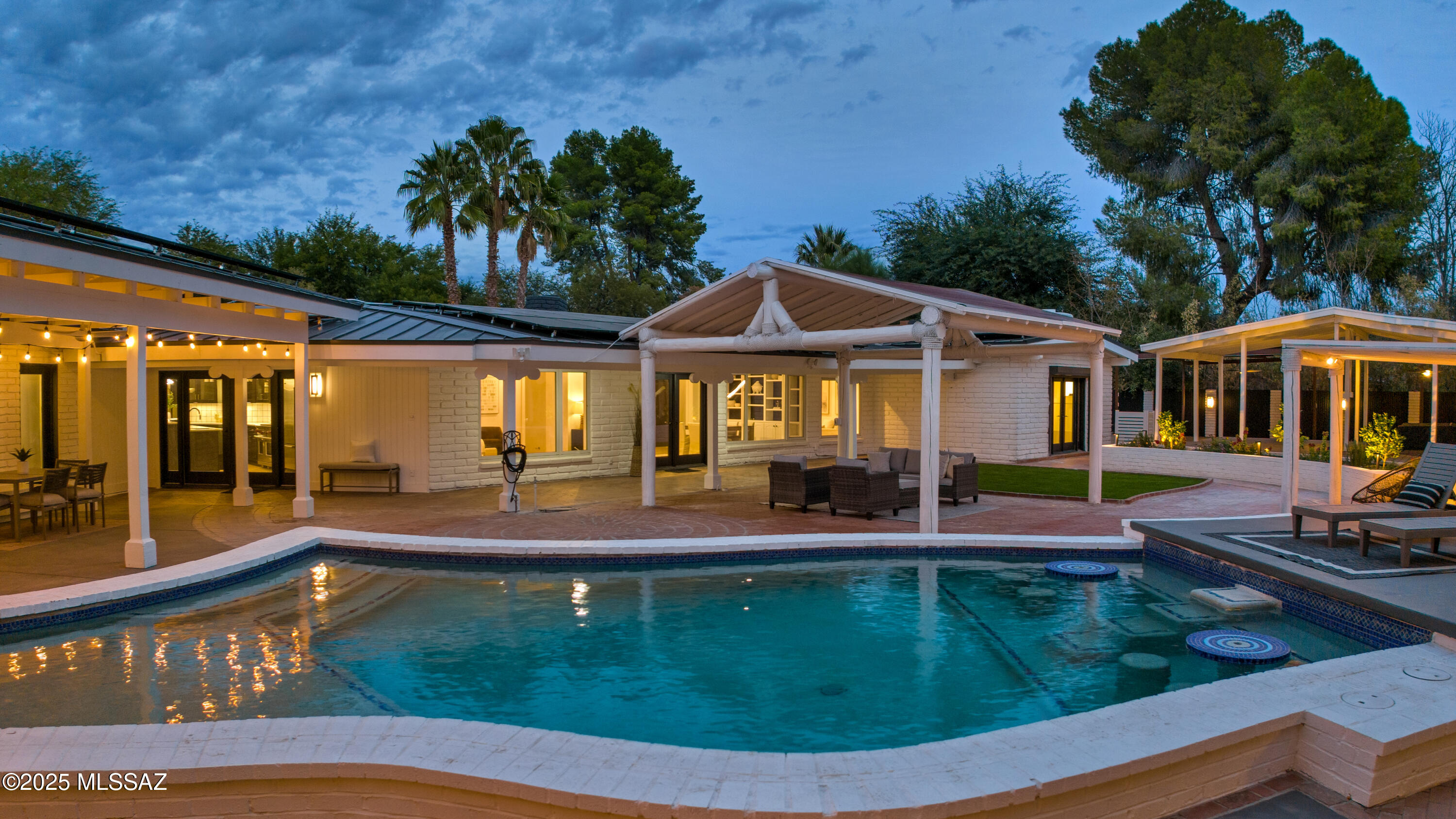 Situated on a premium interior lot in coveted, guard-gated Tucson Country Club Estates, where residents enjoy the best of Arizona living. This sprawling ranch-style burnt adobe home with a modern spin recently underwent an extensive interior renovation and has a new metal roof with new, owned solar panels. A private paradise awaits outside with the resort-style backyard shrouded in lush vegetation, & loaded with amenities. Extensive covered patios create the ultimate environment for year-round outdoor living. Fabulous outdoor kitchen with a built-in BBQ, fireplace with built-in seating, separate outdoor living & dining area, pizza oven, low-care turf area, a gorgeous pool with built-in seating, hot tub, and a sport court. Every inch of this property is finished, starting with the driveway and motor court, which have plenty of guest parking. A diamond-shaped red-brick walkway set in low-care turf bordered by red-brick flower beds leads to a charming courtyard with a fountain, a putting green, and a protected gardening area, creating a magnificent outdoor space to enjoy mountain views & sets the stage for the attention to detail throughout the home. Inside, vaulted tongue-and-groove ceilings and walls of windows showcase abundant natural light and the dreamy, picturesque backyard. Every detail is impeccably crafted, delivering a "wow" moment as you walk in. The classic and the new are carefully merged to retain the essence of the home while bringing it current. Spacious, open kitchen with Sub-Zero and Wolf stainless steel appliances, a center island with a breakfast bar, two dishwashers, two sinks & a wine refrigerator open to the great room with a wet bar, a gas fireplace, and custom built-ins. Just off the great room is an all-new powder room for guests. A den with a modern, built-in fireplace is a flexible space that separates the owner's suite from the main living area. The owner's suite is a private retreat with a fireplace, a new bathroom with a dual sink vanity, custom tile, a new separate vanity area, and an oversized walk-in closet with custom built-ins. The additional bathrooms have brand-new tile, fixtures, vanities, lights, mirrors, hardware, and more. The laundry room is large enough to be a flexible space with tons of storage, including a walk-in cedar closet, perfect for an office, craft room, gift wrapping, or whatever you need. The incredible backyard, which is rarely found, has a new corrugated metal fence with brick column anchors surrounding the entire backyard.

The unparalleled outdoor space presents unlimited opportunities for friends and family to gather & enjoy the Arizona lifestyle. A built-in hot tub that uses electricity generated by the owned solar panels, another massive metal ramada perfect for an outdoor gym or pickleball court, and a side yard with turf and a large net for practicing your golf swing or for pets. In addition to the epoxy-covered floor garage, there is an automatic gate that leads to another covered parking space that could serve as storage for another car. Tucson Country Club is a separate island in the city with a single point of access traversed by two major washes. Homeowners enjoy direct access to the renowned "Loop", a 133-mile interconnected, paved, car-free pathway for walking, running, and biking. Live 10 minutes from everything you need while escaping to your private sanctuary. Just 20 minutes from the University of  Arizona, less than 30 minutes to the Tucson Airport, and close to tons of shopping, great restaurants and bars, and hospitals.