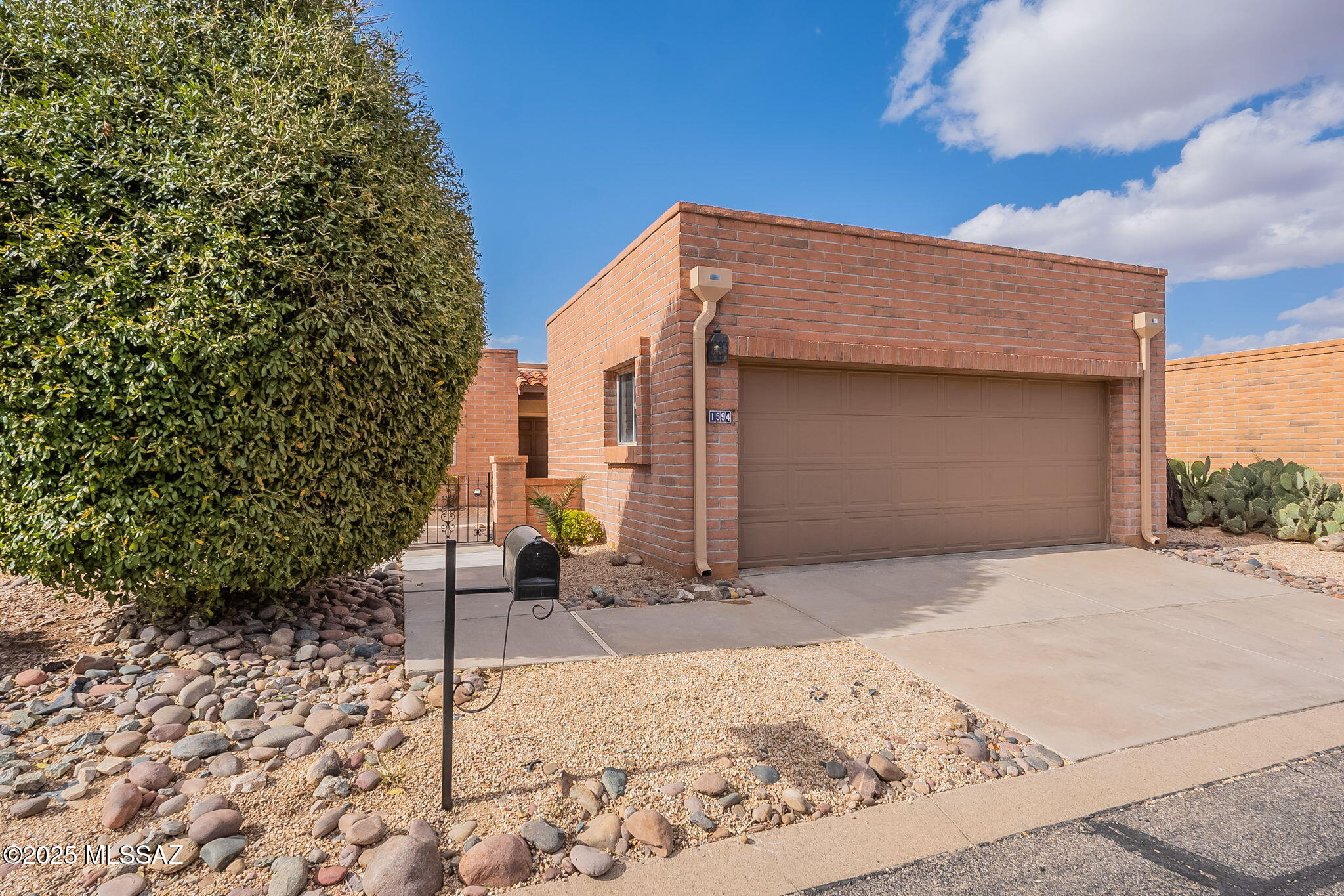 Warm curb appeal welcomes you to this charming Desert Hills home, where red brick accents, mature landscaping, and an inviting courtyard framed by a brick wall and wrought iron gate create a memorable first impression. Step inside to a bright, spacious interior featuring fresh paint and new carpet throughout, with an open living and dining area filled with natural light.

The generously sized kitchen offers plenty of room to gather, complete with a center island with seating, a large breakfast nook, and convenient access to a covered side patio--perfect for enjoying Arizona's indoor-outdoor lifestyle. A comfortable guest bedroom is positioned near the front of the home with views of the courtyard, while the private primary suite is tucked away on the opposite side and features direct access to the covered back patio along with two spacious walk-in closets.

Outside, multiple seating areas and low-maintenance landscaping provide plenty of opportunities to relax, entertain, and enjoy the beautiful Green Valley climate. With its comfortable floor plan, inviting outdoor spaces, and move-in-ready updates, this Desert Hills home is ready to welcome its next owner.