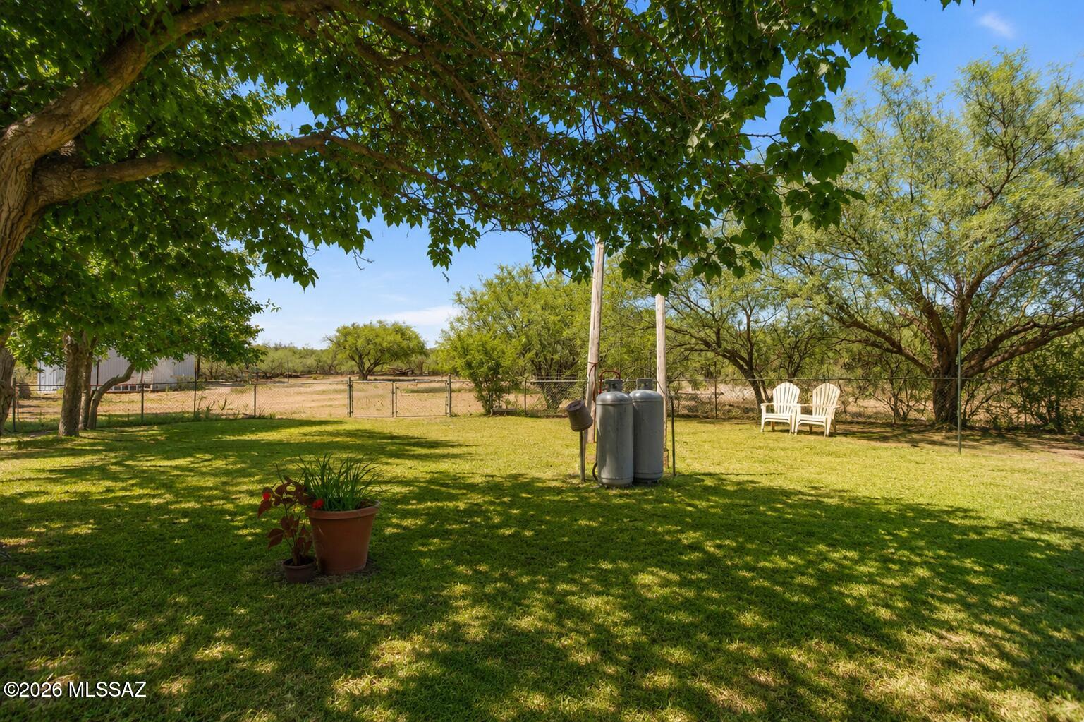 Set on approximately 4 acres in Huachuca City, this distinctive 2-bed, 1-bath home combines character, functionality, and room to spread out. The exterior showcases handcrafted stone construction, creating a memorable first impression, while the interior features exposed wood accents, custom built-ins, colorful design elements, and an open living area anchored by a wood-burning stove and stone fireplace. The spacious kitchen includes ample prep space and a central island. The primary bedroom offers a flexible sitting area, while the second bedroom includes extensive built-in storage and workspace options. Outside, the fully fenced property includes three wells, mature shade trees, multiple outbuildings, a covered workshop structure with a shipping container, and plenty of space to grow, The 5acre vacant land next door is available to purchase for $85,000.
