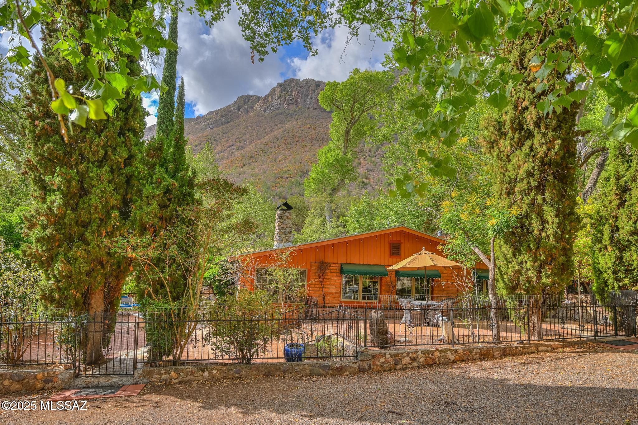 Live in absolute timeless beauty in this 1930s gem nestled on over 4 wooded acres bordering Coronado National Forest. This 3BD/2BA, 2,400 SF retreat features slate & wood floors, a 1934 rock fireplace, 4-season AZ Room, and primary suite w/gorgeous bathroom, clawfoot tub, and stunning views from a private deck. The custom European-style kitchen offers cherry cabinetry, wine cooler, and pantry w/rotating shelves. Enjoy abundant wildlife, amazing seasonal creek, irrigated fruit orchard, (50 trees), she shed, for entertaining and enjoyment. A birder's paradise in Ramsey Canyon beside the Arizona Folklore preserve. and walking distance to Nature Conservancy. This private outdoor sanctuary offers rich soil, 3 wells, and one-of-a-kind charm.