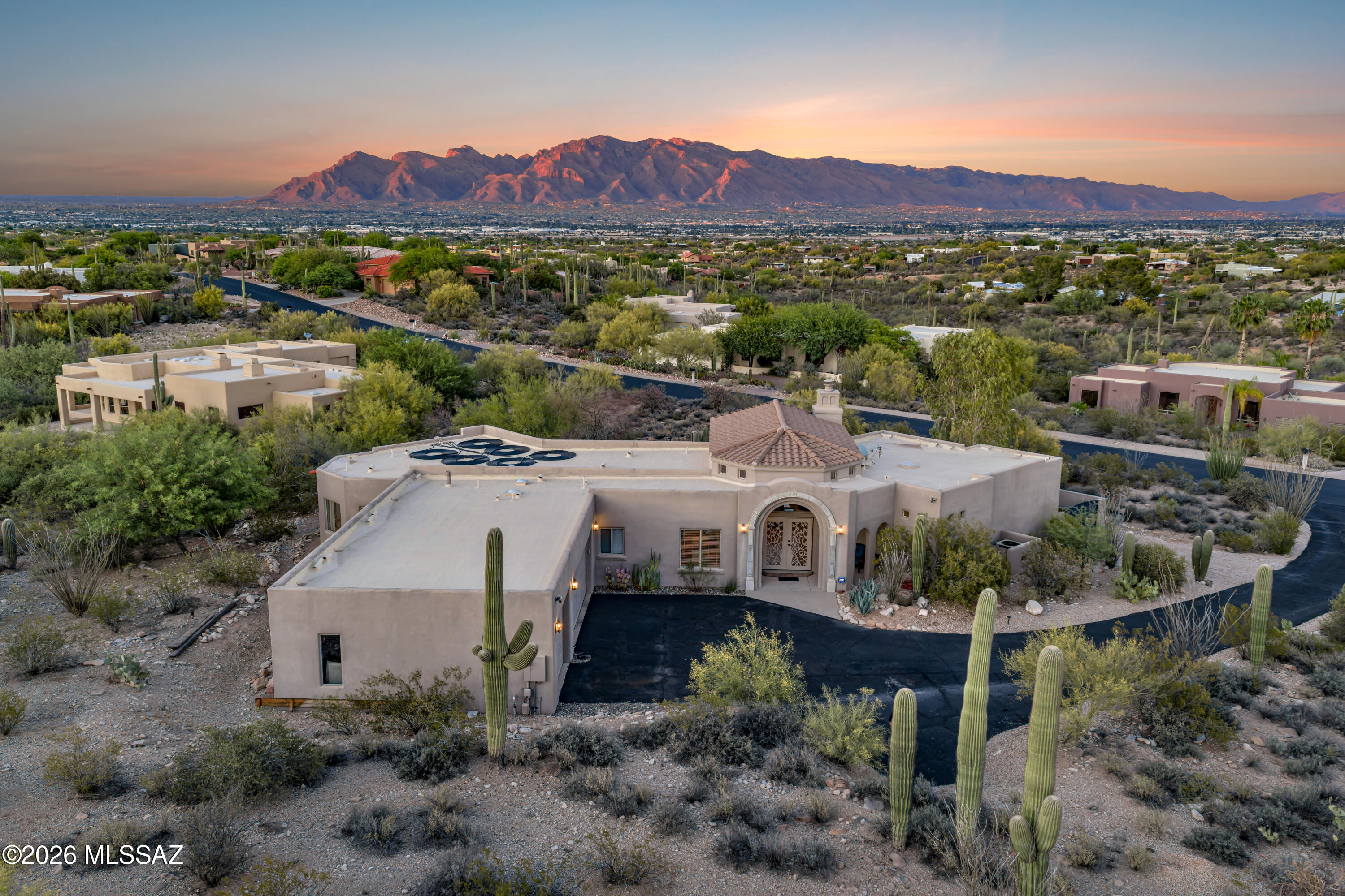 This gorgeous home showcases breathtaking mountain, sunset & city views from inside & out! Beautiful entry welcomes you into soaring ceilings, rich architectural details and elegant travertine floors. Living room features a gas fireplace & dramatic arched window perfectly framing the view. Granite throughout.  Kitchen features a custom live-edge mesquite bartop adjacent to a lovely dining area with cove ceiling. Split floor plan provides privacy, with spacious primary boasting a walk-in closet, dual sinks, walk-in shower and  jetted tub surrounded by windows to take in the abundant desert wildlife. Stunning yard with sparkling pool, hot tub, lrg covered patio and those views! 3-car garage with workshop space and  quiet gated community minutes to vibrant downtown Tucson.
