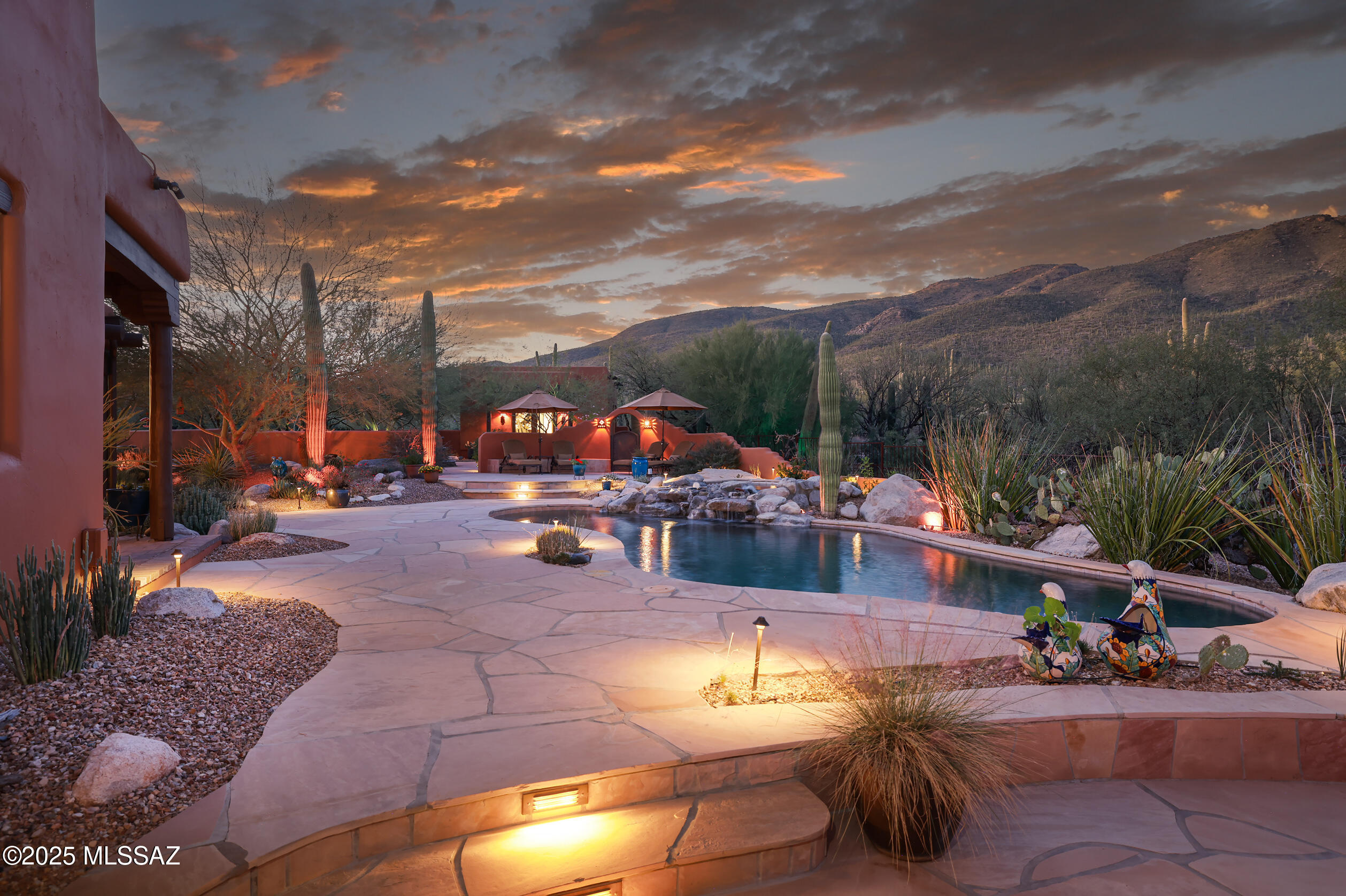 Stunning Ray Birch home, beautifully appointed w/exceptional attention to detail. 4 beds, 4.5 baths & den. Richly accented w/upscale Santa Fe design elements: 3 kiva fp, rustic wood lintels, Saltillo tile & striking wood beam ceilings throughout. Gorgeous kitchen w/Wolf range & custom copper vent hood, live edge leathered granite counters, cherry cabs & custom copper farmhouse sink. Highlights: attached & detached casitas, att 2-car garage w/storage room, det 3-car garage w/HVAC & workshop space, resort-like yard w/mature landscape, flagstone patios, heated pool/spa w/rock waterfall, wrap around patios, outdoor kitchen & wood burning kiva fp, rooftop deck, fully owned solar, water soft, R/O, private well, gated & low HOA. A rare blend of craftsmanship, luxury & breathtaking desert beauty