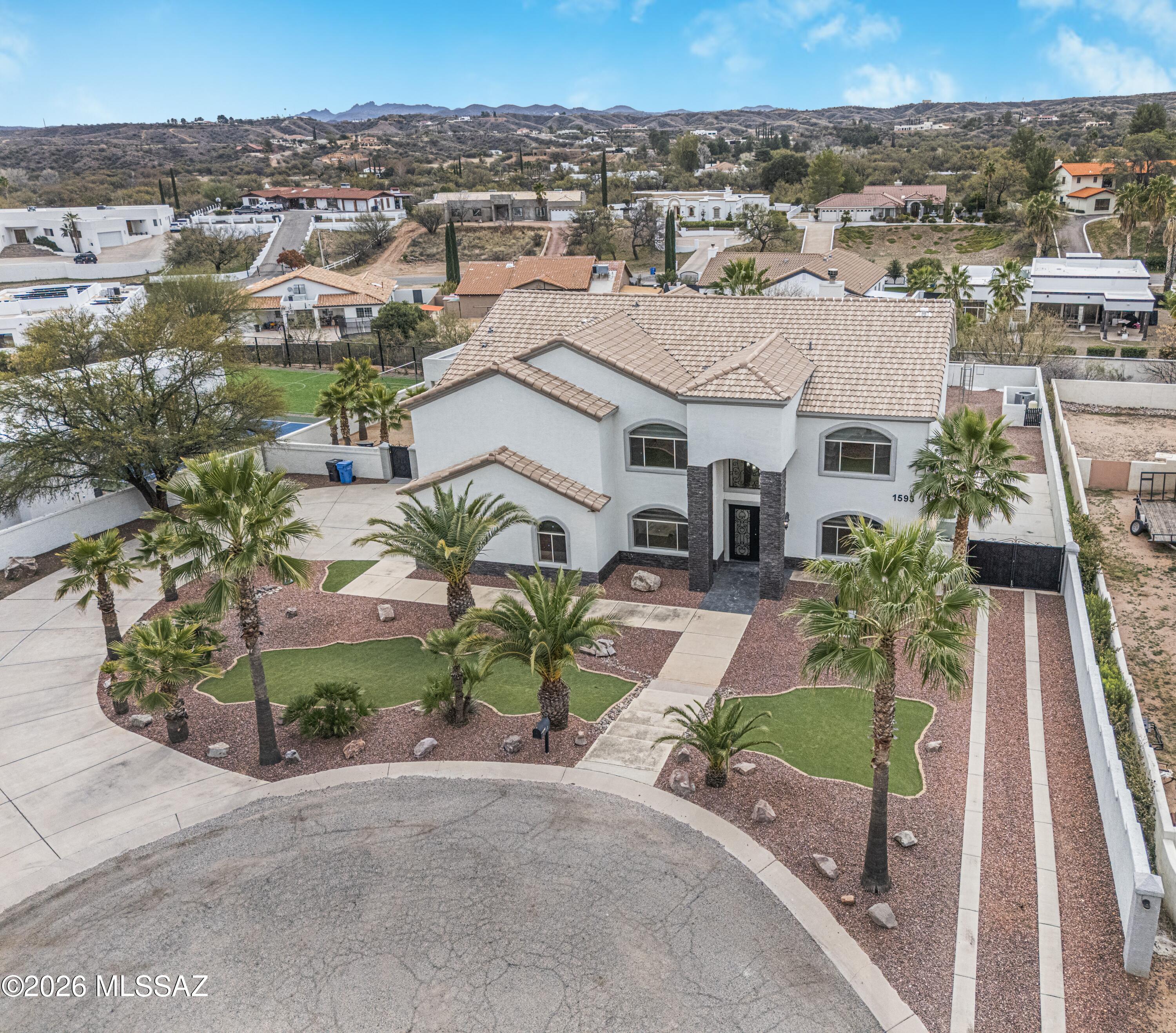 Nestled in an exclusive Nogales enclave, this 4,000+ sq ft estate delivers presence, privacy & timeless design. Impressive steps lead to a pavered front entry with brick-accents. Walk thru glass front entry to soaring cathedral ceilings, a dramatic second-floor hall, solid wood staircase, 2 fireplaces. Flowing travertine tile is complimented by solid wood cabinetry everywhere. The chef's kitchen is exceptional--warm, elegant with dual sinks, gas cook top, sub-zero refrigerator and abundant space to gather. Rooms are grand in scale and must be seen to be fully appreciated. The expansive backyard is an entertainer's dream with room to roam, a pool with slide and unforgettable nights enjoyed from the massive primary suite balcony. Oversized 3-car garage and extra-long driveway & so much more.