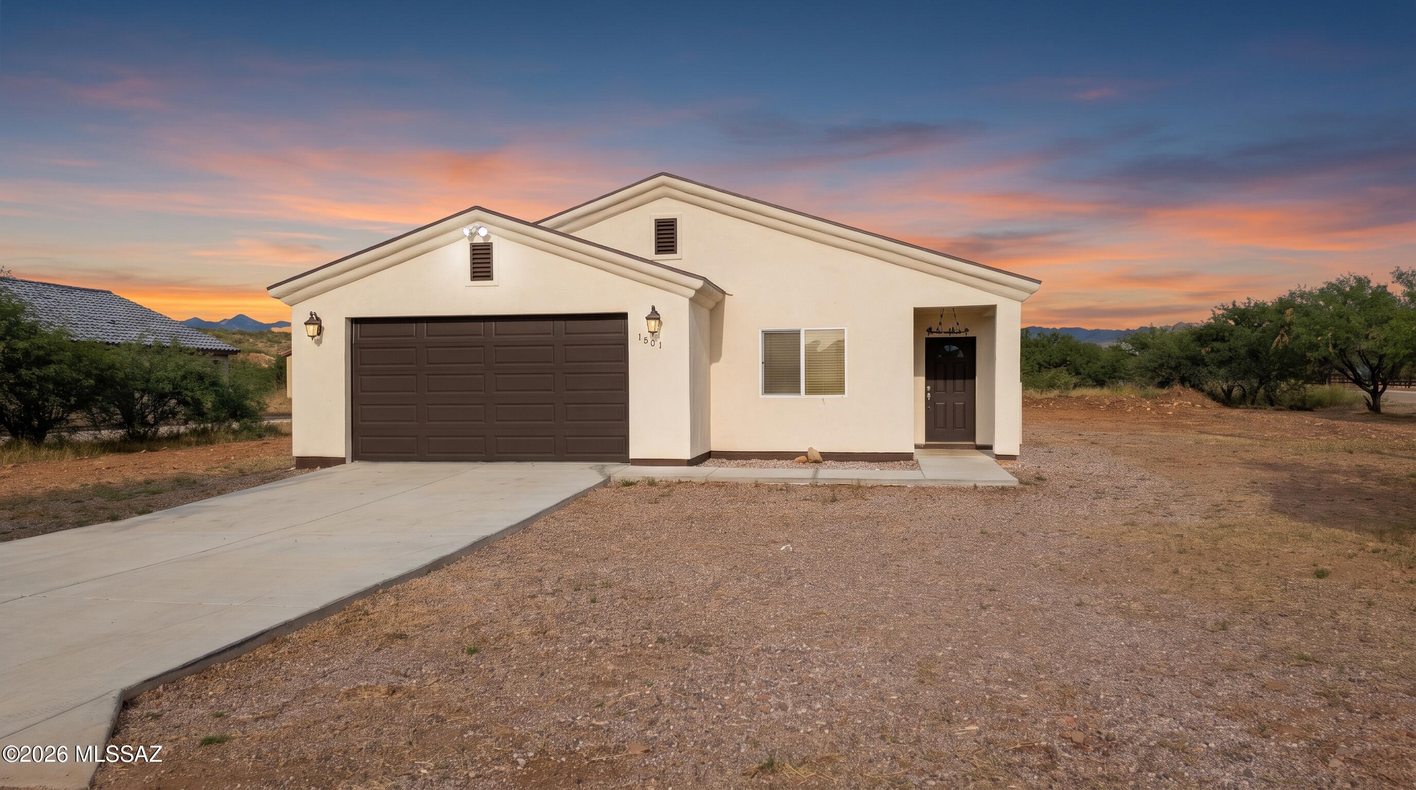 Built in 2023, on sewer, this 1,633-square-foot home in Rio Rico offers modern finishes, an open layout, and room to spread out. Vaulted ceilings, recessed lighting, and wood-look flooring create a bright, welcoming living space. The kitchen stands out with white shaker cabinets, rich espresso lower cabinets, granite countertops, stainless steel appliances, and a spacious island perfect for meal prep or casual dining. Sliding glass doors bring in natural light and connect the dining area to the outdoors. Outside, the large lot offers plenty of space for landscaping, outdoor living, or additional parking. A two-car garage and wide concrete driveway add everyday convenience. Enjoy modern living with extra room to make the property your own.