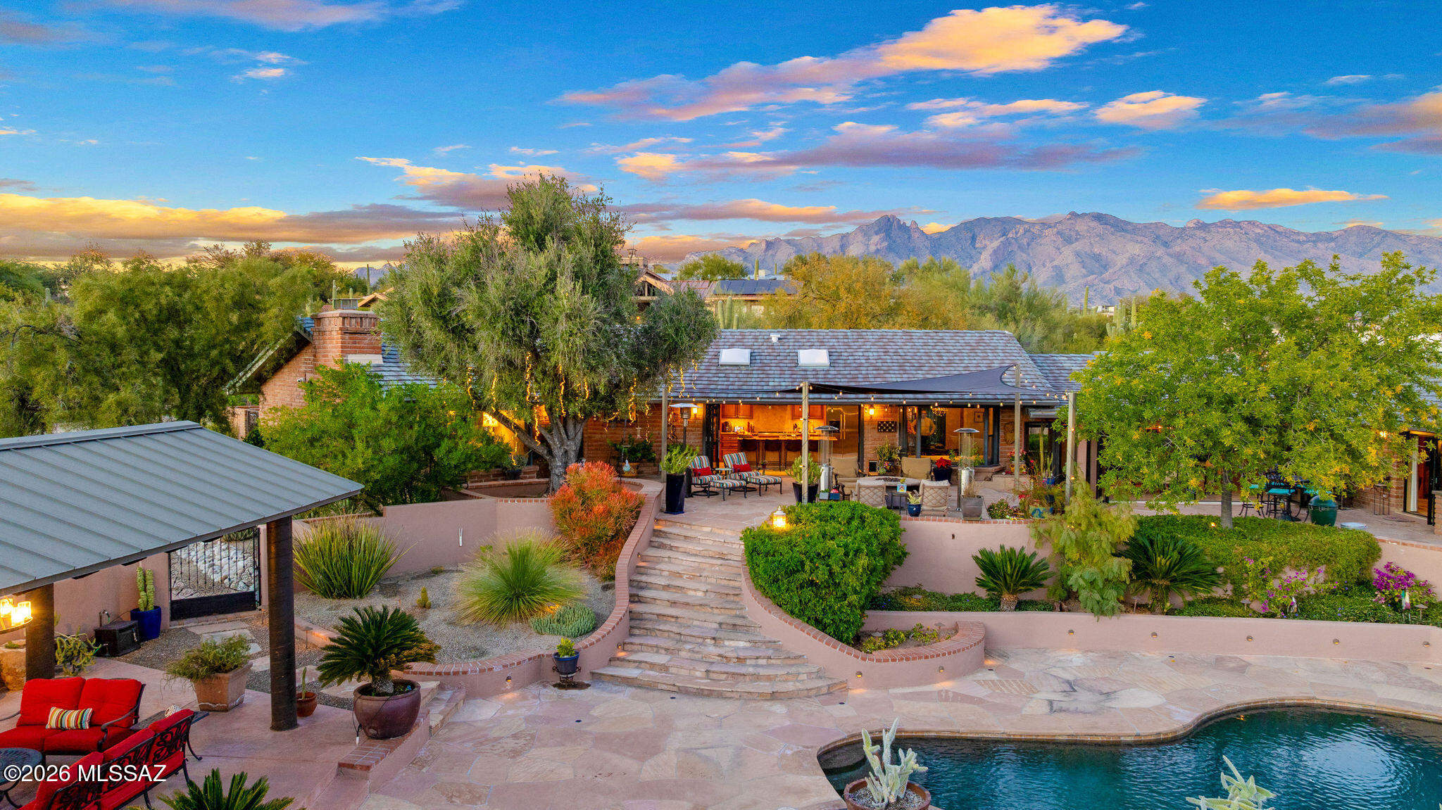 Set behind gates on 1.39 acres in Tucson's coveted Catalina Foothills, this architecturally distinctive 1961 burnt adobe California Ranch blends timeless character with thoughtful modern upgrades. Single-level living, warm materials, and seamless indoor-outdoor flow define a property designed for both everyday comfort and elevated entertaining--without HOA restrictions.
The main residence and separate guest house total 4,671 square feet, offering five bedrooms and four-and-a-half baths with flexibility for multigenerational living, guests, or a private home office. Vaulted wood ceilings with exposed beams, expansive glass, energy efficient double pane windows, plantation shutters throughout, stone tile flooring and abundant natural light create an inviting sense of space while honoring the home's mid-century roots. At the heart of the home, the living and dining areas open effortlessly to the outdoors, where retractable glass walls connect interior spaces to a terraced backyard oasis. The kitchen and adjacent dining and living rooms are positioned for gatheringwhether hosting large celebrations or enjoying quiet evenings by one of the home's three gas fireplaces.
The primary suite is privately situated and designed as a true retreat, featuring a walk-in closet and a spa-inspired bath with heated floors, full slab granite counter tops w/dual vanities, a soaking tub, and a multi-head shower. Three additional bedrooms and two baths are thoughtfully arranged to provide privacy and comfort.
A short walk through the manicured landscaped grounds leads to the separate 508-square-foot guest house, offering its own living area, kitchenette, bedroom, bath, and private outdoor spacemirroring the refined finishes of the main home and ideal for extended stays.
Outdoors, the property lives like a private resort. A heated saltwater Pebble Tec pool, covered ramada with fireplace, outdoor grill, fountains, and multiple seating areas are surrounded by mature desert landscaping, fruit trees and panoramic mountain views. There is ample room for horses, RV parking, and additional vehicles, all within a fully fenced, gated and secure setting.
Recent ownership brought extensive upgrades focused on infrastructure, technology, and ease of living. Approximately $200,000 in improvements include a comprehensive security and camera system with full perimeter coverage, restored and expanded landscape irrigation and lighting, plumbing and electrical upgrades, a whole-house water conditioning system, updated pool equipment, refreshed exterior paint, and a new mini-split HVAC system for the guest house. The main home features three zoned HVAC systems, while the 459-square-foot garage is heated and cooled, adding year-round functionality.
Originally built in 1961 and carefully stewarded through generations, this Hacienda Del Sol estate offers rare authenticity paired with modern reliability. Enjoy privacy just minutes from dining and shopping, it delivers a tranquil Foothills lifestyle with architectural character that is increasingly hard to find.
Highlights:
~1.39-acre gated Foothills property | No HOA
~4,671 SqFt total | 5 beds | 4.5 baths | Single story
~Separate guest house with kitchenette w/private outdoor space
~Heated saltwater Pebble Tec pool & covered ramada with fireplace
~Burnt adobe construction, vaulted beam ceilings, retractable glass    walls
~Three zoned HVAC systems + guest house mini-split
~Heated/cooled garage, RV parking, horse property zoning

A rare opportunity to own a legacy Foothills propertyarchitecturally warm and effortlessly livable.