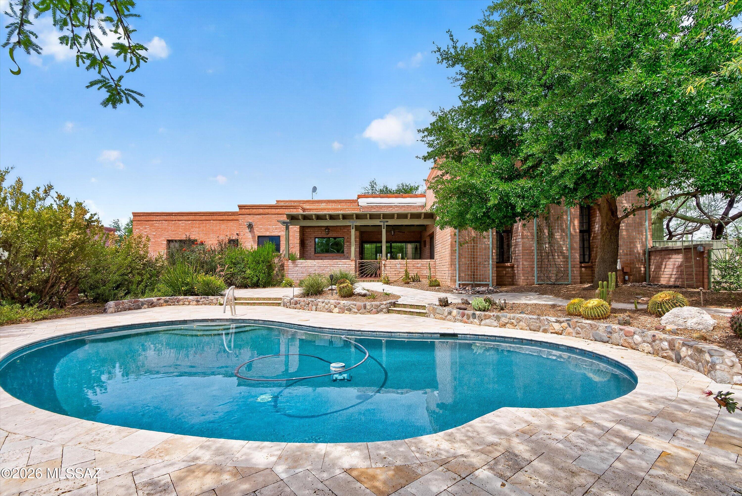 Owner/Agent. Exceptional Tanque Verde Valley masonry hacienda in prestigious La Cebadilla Estates sits on over four acres of lush desert with panoramic views of the Rincon mountains. The circular drive leads to a cozy entry courtyard with a west-facing covered patio perfect for enjoying cool mornings. Inside the home, a soaring entry hall opens into the great room with expansive windows and a fireplace to gather around on chilly evenings. The open chef's kitchen with a large island, alder cabinetry and Sub-Zero and Miele appliances is perfect for casual entertaining. Relax in the primary suite, which features another fireplace, an en-suite bath with a soaking tub, and a large walk-in closet. The second and third bedrooms share a bath at the front of the house. The fourth bedroom sits on the other side of the house with an en-suite bath and a private patio, making it perfect for guests. Artistry abounds throughout the home with carefully curated design details creating a warm blend of classic Tucson territorial style updated for modern living. Outside the pebble tec pool beckons, surrounded by travertine patios and colorful plantings. Enjoy a fire in the outdoor fireplace or entertain in the outdoor kitchen. Situated next to the main house, the 943-square-foot studio with a garage door features a kitchenette with a sink and a mini-fridge plus a full bathroom. Fully heated and cooled, the studio offers options--an artist studio, a garage workshop for a car collector or a guest suite. Walk or ride horses on the community trails to the private lake or head across the Tanque Verde Wash to the Saguaro National Park. Award-winning Tanque Verde schools. Southwestern desert living at its finest.