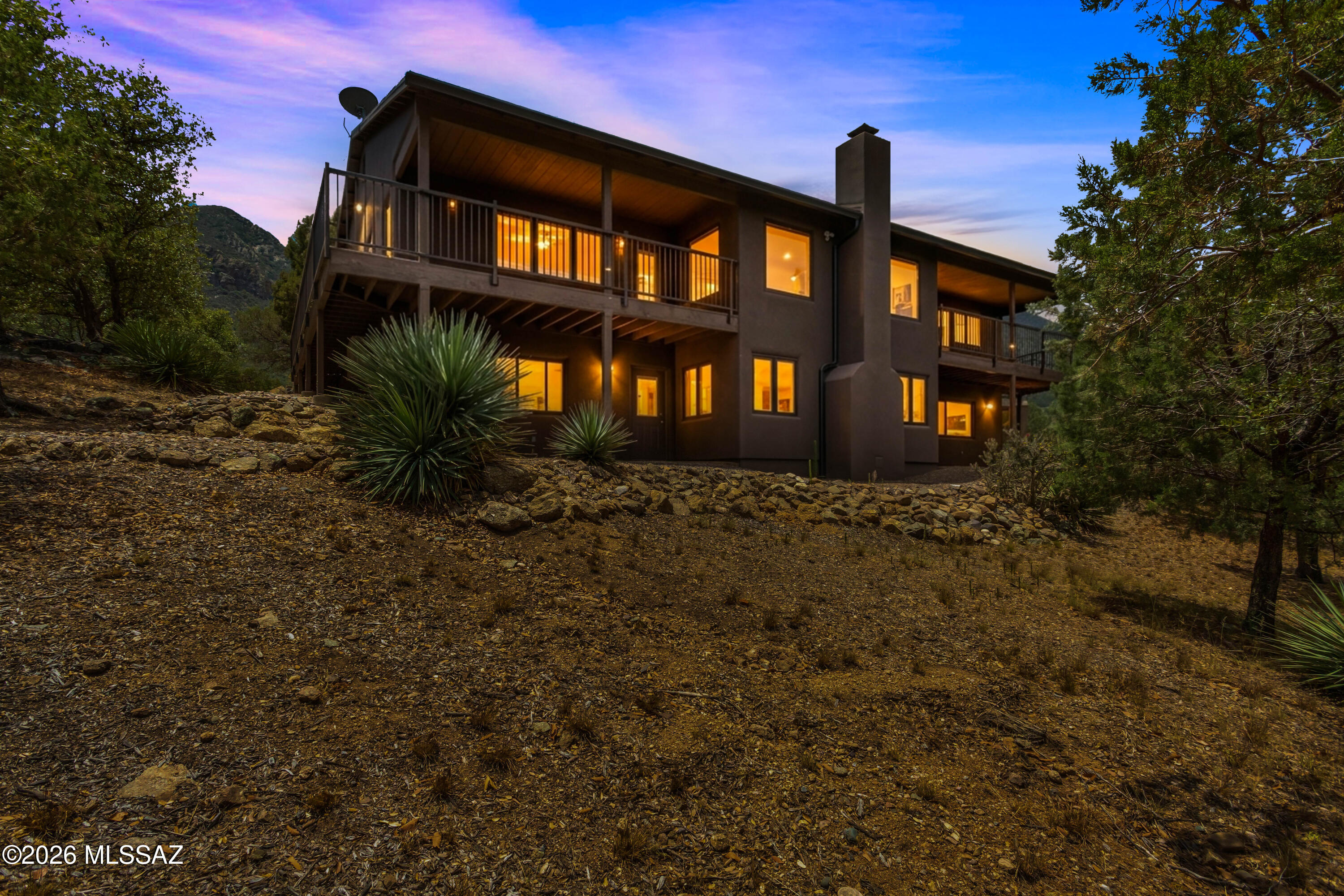 Nestled in the heart of desirable Ramsey Canyon, this custom-built home offers the perfect blend of craftsmanship, comfort, & breathtaking natural beauty. Quality details abound, including custom knotty alder soft-close cabinetry/vanities, matching knotty alder interior doors, baseboards, & window trim throughout. Enjoy spectacular mountain views & twinkling city lights from the expansive covered deck that wraps around two sides of the home. A screened breezeway provides convenient access to the detached 2-car garage while creating the perfect space to enjoy the peaceful canyon setting. The well-appointed kitchen features Corian countertops, a center island, and abundant storage. Designed for flexibility, the fully finished lower level functions as a second living space complete with its own full kitchen, bedroom, bathroom, wood-burning fireplace, private entrance, and two covered patios--ideal for multigenerational living, guests, or entertaining. Interior stairs connect both levels for seamless access.

Additional amenities include 18x30 covered RV parking garage, covered carport, storage shed, water conditioning system, and all-electric utilities. Surrounded by abundant wildlife and serene canyon landscapes, this exceptional property offers a rare opportunity to escape the city and enjoy the tranquility of Southern Arizona living.