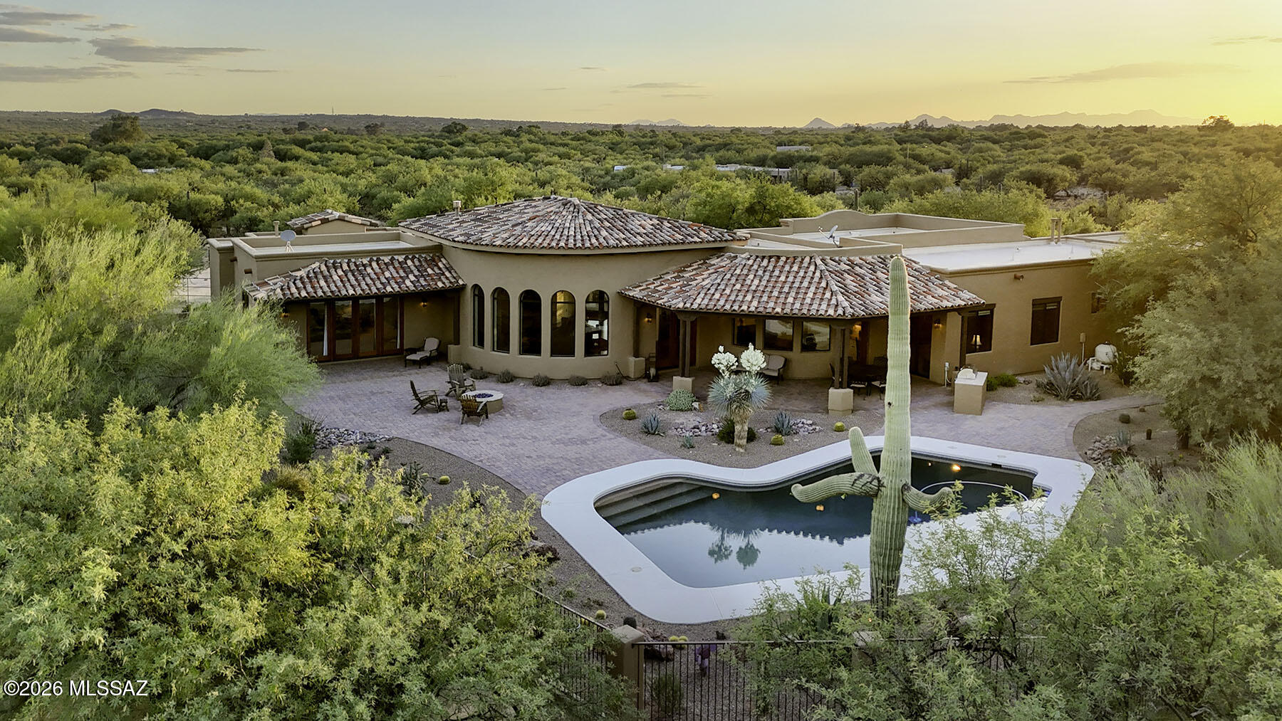 Experience the pinnacle of desert luxury in this 2019, privately situated 5,159 sq. ft. 5 bedroom, 4 bath home, within the prestigious La Cebadilla Estates. Being sold fully furnished, and replete with the 5th bedroom that is a self-contained guest quarters, this exceptional residence offers breathtaking panoramic mountain views on over 3 acres of pristine horse property, delivering a rare blend of elegance, comfort, and serene Southwestern living.  From the moment you enter, you're welcomed into a grand living room with soaring ceilings, an elegant fireplace, and expansive windows that perfectly frame the surrounding natural beauty. The home seamlessly blends indoor and outdoor living, bringing the desert landscape into every space.  The gourmet kitchen is designed for both everyday living and entertaining, featuring granite countertops, a large center island, breakfast bar, wine refrigerator, warm alder wood cabinetry, premium stainless steel Monogram appliances, and a spacious walk-in pantry. A bright breakfast nook surrounded by windows completes the space. The home offers two luxurious primary suites . . . the main suite showcases stunning Rincon Mountain views through a wall of windows and includes a spa-like ensuite bath with split vanities, an oversized shower, and a generous walk-in closet. The second primary suite also features a beautifully appointed ensuite bath with dual vanities, a large shower, and ample closet space.  The fully equipped guest quarters provides ultimate flexibility, complete with a private entrance, bedroom, living room, full kitchen with granite countertops, bathroom, and its own outdoor patio, ideal for extended family or guests.  Additional interior highlights include a private office/den with custom built-in bookcases, a formal dining room with wood beam accents, warm wood-grained ceramic tile flooring throughout, and picturesque views from every window.  Step outside to an exceptional outdoor living area designed to take full advantage of the sweeping mountain views. Enjoy the covered wraparound patio, built-in BBQ, outdoor dining space, glass firepit, and a stunning pool, all set against the dramatic desert backdrop.  Property features include 3.25-acre saguaro-studded lot with mature trees; panoramic views of the Rincon and Catalina Mountains; quiet, private, and peaceful setting with abundant wildlife; horse facilities including 4-stall barn, arena, and direct trail access; access to subdivision trails leading to Saguaro National Park; expansive pool and outdoor entertaining areas; 5.1 surround sound system with 85-inch Sony 4K TV; post-tension slab construction and 2"x 6" framing; exterior freshly painted in 2025; spectacular sunset views. This is a rare opportunity to own a refined desert retreat that perfectly balances luxury living with natural beauty and equestrian lifestyle.