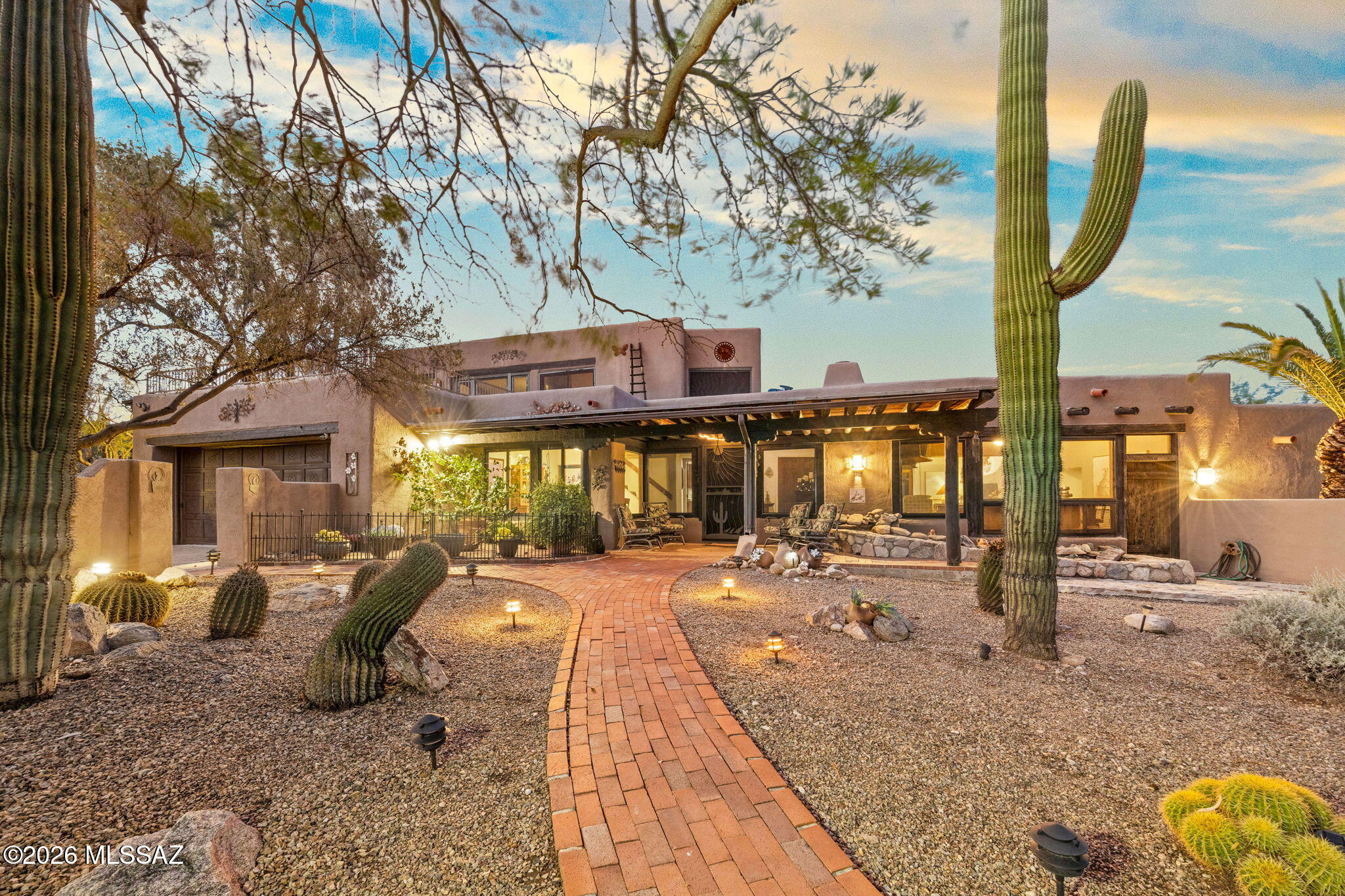 Custom Santa Fe home nestled in the Catalina Foothills with breathtaking mountain, sunrise, and sunset views. This exceptional property features four fireplaces, including a stunning Kiva fireplace with a built-in bar, spacious primary suite on the main level, and three tranquil water fountains. Enjoy true Arizona living with a resort-style pool featuring a cascading waterfall. Inviting outdoor spaces designed for entertaining including a built in kitchen, ramada, and covered patio area. The detached guest quarters offer a bedroom, living area, and kitchenette, providing the perfect space for guests or multigenerational living. Complete with an expansive paver driveway and timeless Santa Fe architecture, this is Foothills living at its finest.