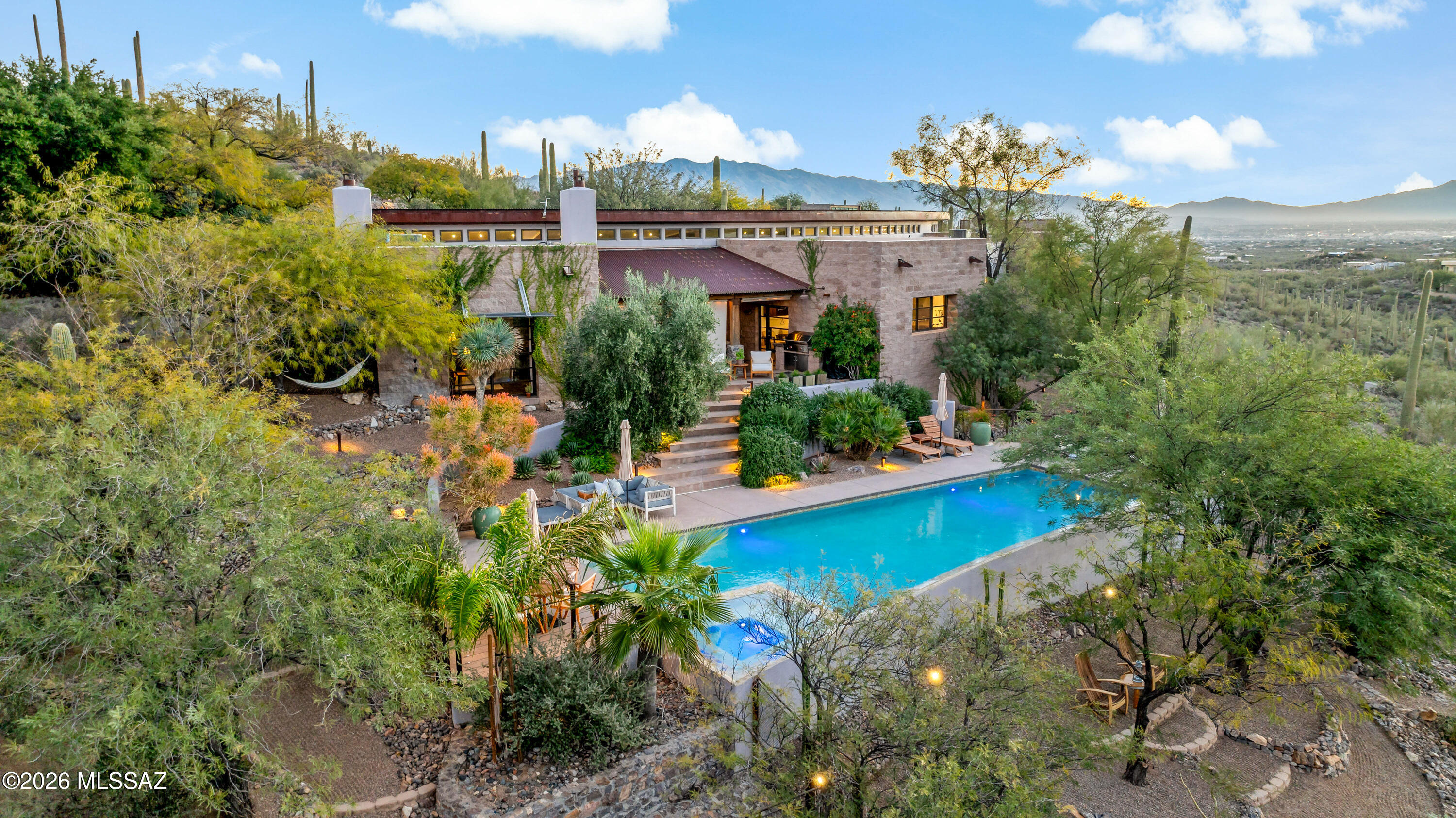 Welcome to La Villa Serena--a private desert sanctuary bordering Saguaro National Park in secluded Chaos Canyon, where extraordinary privacy, architectural significance, and resort-style living meet just minutes from the city.

Set on approximately six acres with no HOA, this one-of-a-kind contemporary estate offers 4,425 square feet of thoughtfully designed living space, including a guest house, studio or fourth bedroom, and a dedicated library--creating exceptional flexibility for guests, multigenerational living, creative space, or a private retreat.

Designed on a dramatic curved arc, the residence is both bold and timeless, blending rugged stone, concrete, and steel with refined modern finishes, custom iron windows, gallery-style lighting, and three fireplaces that add warmth and intimacy throughout.

Walls of glass frame expansive mountain, saguaro, and sparkling city-light views while seamlessly connecting indoor and outdoor living. The resort-style grounds were designed for restoration and entertaining alike, featuring a large pool, covered patio with fireplace, misting system, Zen garden with soaking tub, outdoor shower, and more than half a mile of private walking trails winding through the desert landscape.

La Villa Serena is more than a home--it is a rare opportunity to own a secluded luxury retreat where peace, design, and nature exist in perfect balance.

For additional details, please see the documents section and visit www.lavillaserena.com.