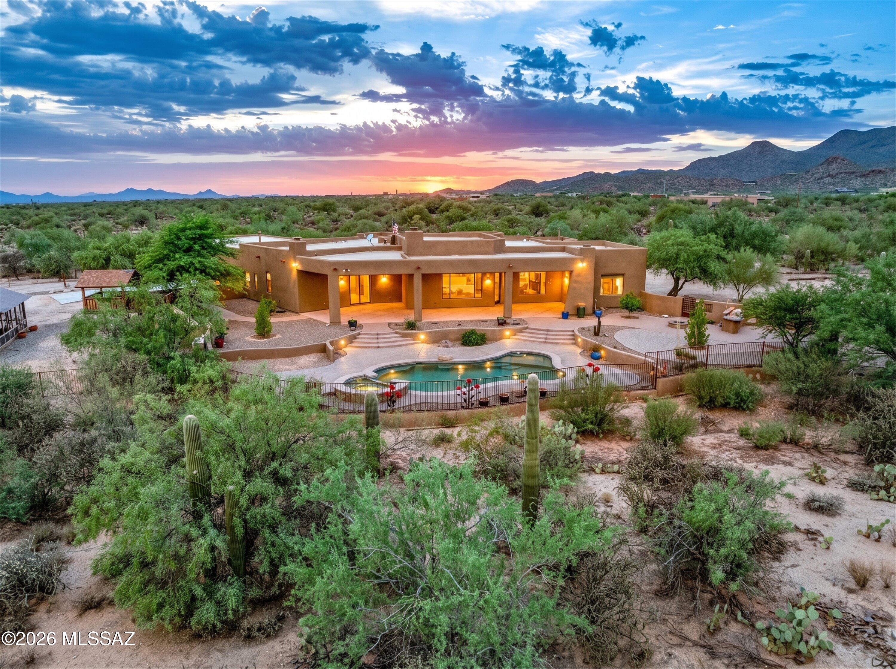 This Santa Fe stunner is situated on 3.3-acre offering 3,770 sq ft of authentic Tucson living, highlighted by breathtaking mountain views! This home blends a classic touch of rustic with grand-scale entertaining spaces in a popular split-bedroom floor plan. Enter into the heart of the home, an expansive great room featuring a cozy fireplace and a dramatic wall of windows framing panoramic mountain vistas. The custom chef's kitchen is detailed with alder cabinetry, a unique cooking alcove, a central island, and a dedicated dining area. A bonus family room provides the ultimate flex space for a pool table or additional living area. The primary suite is spacious and complete with a soaking tub, separate shower, dual vanities, and custom rock accents. The interior layout is versatile, as the large office/den can easily convert into a 4th bedroom alongside the existing 3 beds and 4 baths. The dining area could double as an extra office/exercise room. Outdoor amenities include a sparkling saltwater pool and hot tub; built in BBQ area with firepit; garden areas; children's play fort; and a custom chicken coop as well!  Car enthusiasts and hobbyists will appreciate the climate-controlled, oversized 4-car garage, which comes fully equipped with tons of storage cabinets (as well as an additional storage room); 2 EV chargers; workshop area, and its own private bathroom. NO HOA; shared well; close to shopping, dining, hospitals, I-10 and more. This one checks all the boxes! CHECK OUT THE VIDEO HOUSE TOUR!