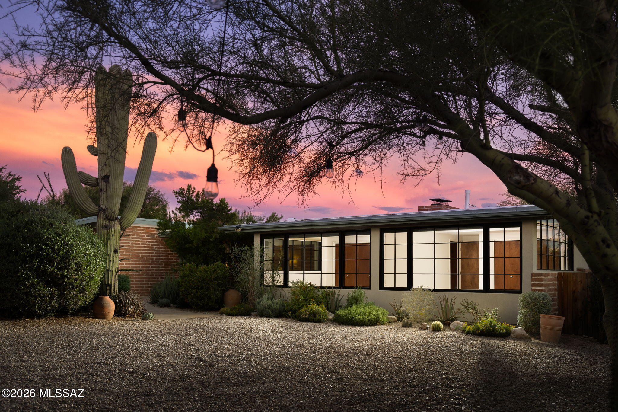 Flawless Mid-Century Modern seamlessly blends luxurious modern comforts w/the era's original charm. Incredibly private, gated & sited on 2.85 lower Foothills acres, far from the road & neighbors. Lush gardens, nourished by a private well, lead along a winding path to the residence. Walls of view windows, exposed brick, fireplace & sloping white wood-beam/plank ceilings define the architecture. The kitchen pairs premium modern appliances w/classic MCM design. Remodeled spa-like baths add luxury & function, while an impeccably maintained original bath honors the era. Polished floors & natural light flow to a deep covered patio for seamless indoor/outdoor living. Gardens feature citrus & olive trees, greenhouse, spa w/cooling feature & stone Argentinian grill w/built-in wood/coal pizza oven.