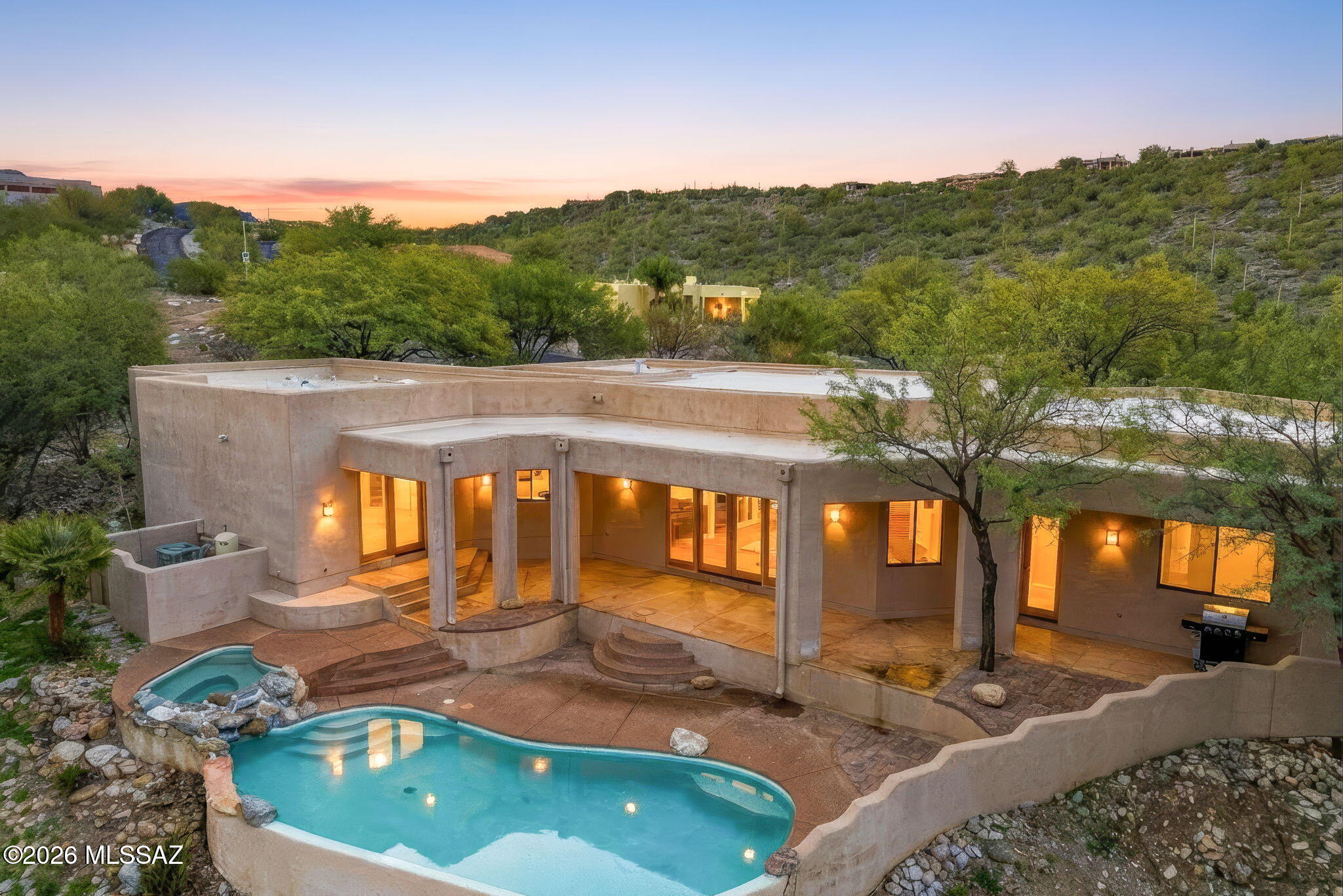 Tucked away at the end of a quiet cul-de-sac, this 4-bedroom contemporary Southwestern home offers refined desert living in a relaxed, private setting within the Catalina Foothills. Perfect for multigenerational living! The 4th bedroom has a large ensuite! Surrounded by mature trees and natural desert landscape, the home enjoys mountain views, city lights, and star-filled skies. Designed for effortless indoor-outdoor living, the backyard features a negative-edge pool and in-ground spa, along with hand-crafted stone seating areas—perfect for entertaining or unwinding at day's end. With exceptional privacy and ample parking, this is a truly special foothills retreat.