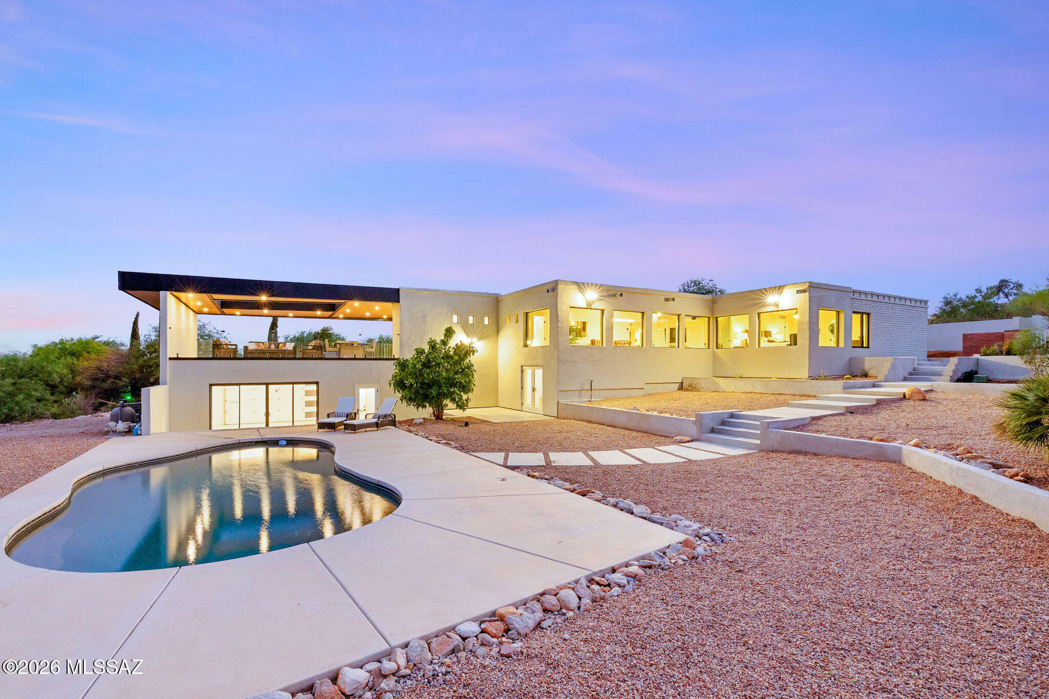 Perched at the end of a quiet cul-de-sac in one of the Catalina Foothills' most desirable neighborhoods, this beautifully reimagined contemporary residence offers the perfect balance of architectural style, privacy, and breathtaking mountain views!
Thoughtfully renovated with an unmistakably modern aesthetic, every space reflects exceptional pride of ownership and a commitment to quality! Expansive windows frame the surrounding Catalina Mountains while filling the home with natural light, creating a seamless connection between the interior and the spectacular desert landscape.
Designed with entertaining in mind, the heart of the home is an impressive chef's kitchen featuring honed marble countertops, custom cabinetry, updated premium appliances, dual dishwashers, wine refrigeration, warming drawer, and generous gathering spaces that effortlessly flow into the dining and living areas! Just beyond, a striking skybridge creates one of the home's signature architectural moments, offering a dramatic transition to outdoor living while capturing unforgettable mountain vistas!
The spacious primary suite provides a true retreat, complemented by beautifully updated baths, generous guest accommodations, and flexible living spaces that easily adapt to today's lifestyle. Every improvement has been carefully considered--from expanded windows and refined finishes to thoughtful structural enhancements--resulting in a home that feels both timeless and current!
Outside, multiple patios and outdoor living spaces invite year-round enjoyment of Tucson's renowned climate, whether hosting friends under the stars or enjoying a quiet morning coffee surrounded by the beauty of the Foothills! The end-of-cul-de-sac setting provides outstanding privacy with minimal traffic, creating a peaceful environment that is increasingly difficult to find.
Combining sophisticated design, exceptional craftsmanship, remarkable mountain views, and an unbeatable Foothills location, this is a rare opportunity to own a move-in-ready contemporary residence where every detail has been thoughtfully curated for modern Arizona living!
