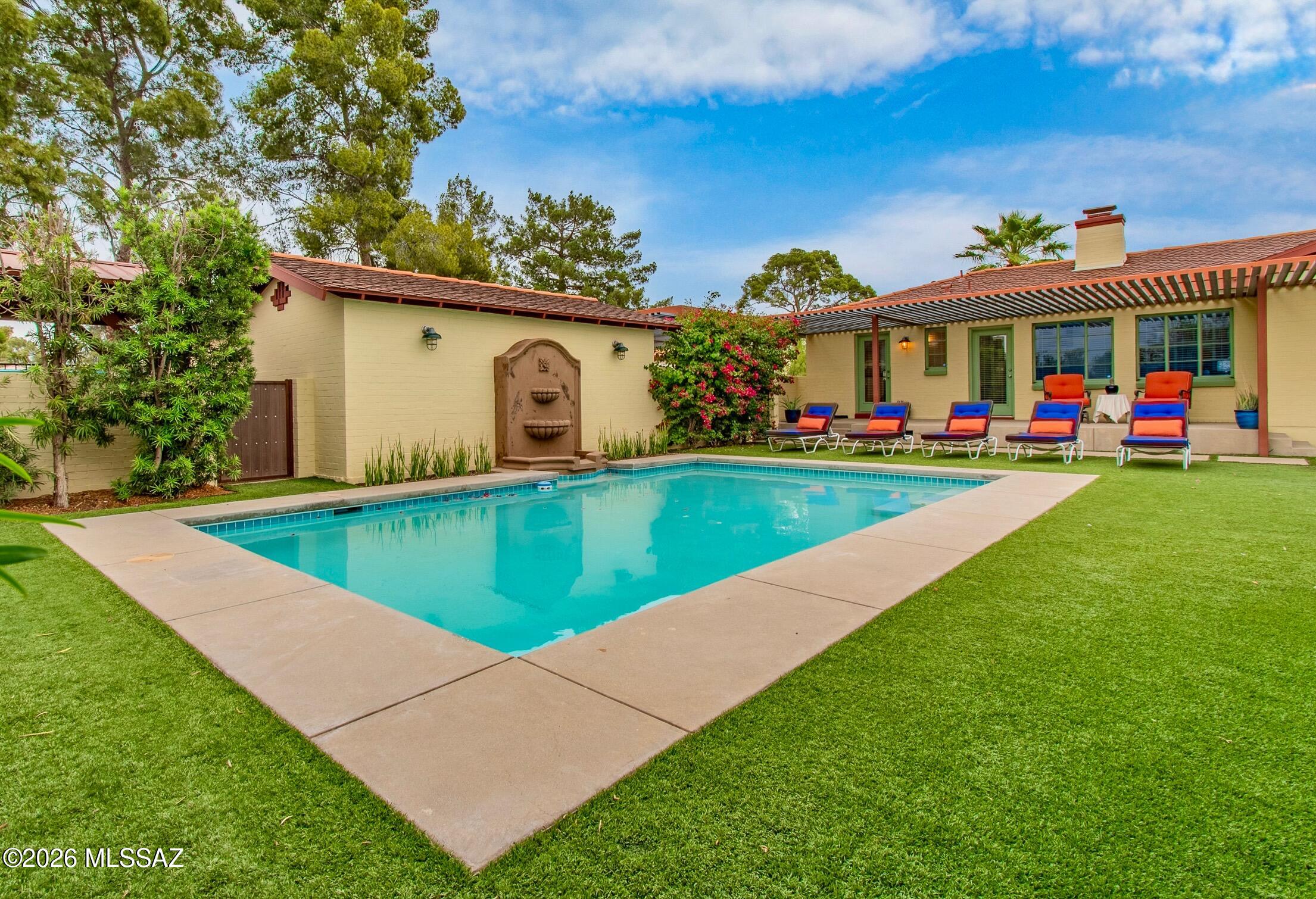 Set along a historic Tucson street in the Catalina Vista Neighborhood, this thoughtfully designed property features two distinct and refined residences that work together as a cohesive compound.
Outdoor spaces are central to the experience, with great attention to detail. A pebble-finish pool and water feature, synthetic lawn, and layered landscape of desert specimen plantings and raised garden beds create a manicured setting for year round enjoyment. An outdoor shower and well equipped kitchen with sink, grill, and Green Egg support year-round use, while a one-car garage and two-car carport integrate with the main residence.
The primary house offers two elegant bedrooms, one-and-a-half bathrooms, and a dedicated office oriented toward the spectacular yard. Interior details reflect a balance of Spanish influences and thoughtful updates, including hardwood floors, coved ceilings, Talavera tile accents, custom built-ins, and designer lighting. Plantation shutters frame views to the surrounding outdoor spaces, reinforcing the connection between inside and out.
The guest house is designed with intention and clarity, functioning as a one-bedroom residence with a spacious bathroom and its own laundry room. The kitchen includes quartz countertops, ample storage, and integrated dining space, while French doors along the north side of the great room bring in copious natural light. Concrete floors, modern millwork, and vintage enamel lighting create a layered mix of materials that complement the main home.
Together, the two structures offer impeccably executed flexibility for multigenerational living, guest accommodations, or a dedicated workspace, all within a setting that emphasizes design continuity, outdoor living, and idyllic Tucson character.  This property has Historical Tax status.