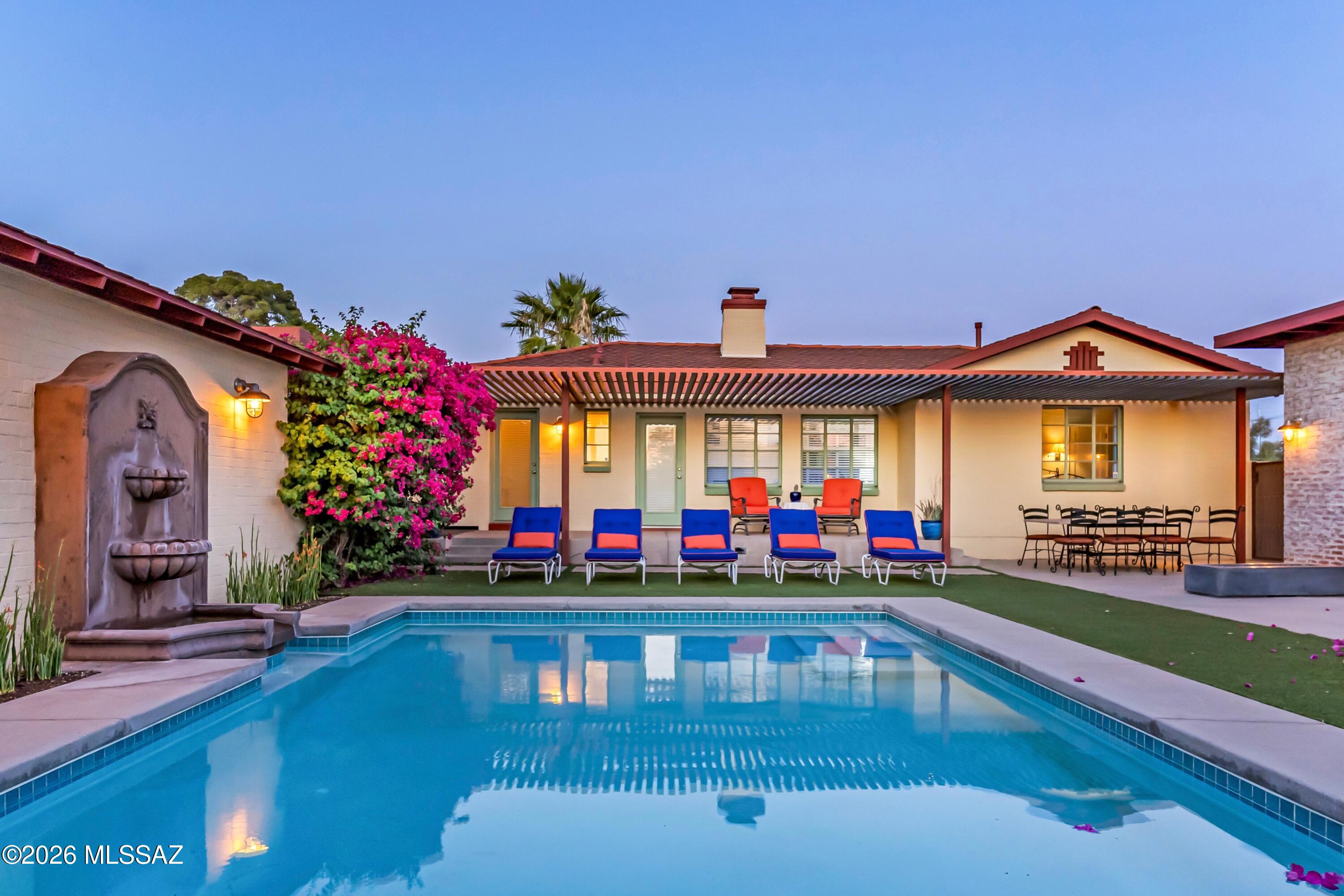 Set along a historic Tucson street in the Catalina Vista Neighborhood, this thoughtfully designed property features two distinct and refined residences that work together as a cohesive compound.
Outdoor spaces are central to the experience, with great attention to detail. A pebble-finish pool and water feature, synthetic lawn, and layered landscape of desert specimen plantings and raised garden beds create a manicured setting for year round enjoyment. An outdoor shower and well equipped kitchen with sink, grill, and Green Egg support year-round use, while a one-car garage and two-car carport integrate with the main residence.
The primary house offers two elegant bedrooms, one-and-a-half bathrooms, and a dedicated office oriented toward the spectacular yard. Interior details reflect a balance of Spanish influences and thoughtful updates, including hardwood floors, coved ceilings, Talavera tile accents, custom built-ins, and designer lighting. Plantation shutters frame views to the surrounding outdoor spaces, reinforcing the connection between inside and out.
The guest house is designed with intention and clarity, functioning as a one-bedroom residence with a spacious bathroom and its own laundry room. The kitchen includes quartz countertops, ample storage, and integrated dining space, while French doors along the north side of the great room bring in copious natural light. Concrete floors, modern millwork, and vintage enamel lighting create a layered mix of materials that complement the main home.
Together, the two structures offer impeccably executed flexibility for multigenerational living, guest accommodations, or a dedicated workspace, all within a setting that emphasizes design continuity, outdoor living, and idyllic Tucson character.  This property has Historical Tax status.