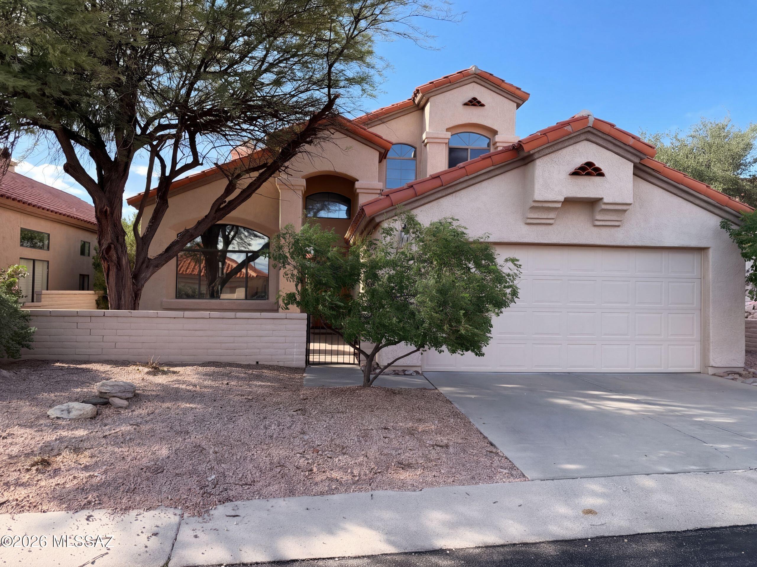INCREDIBLE BUYER INCENTIVES: $11,000 MORTGAGE CONCESSION. Seller will pay up to $11,000 at closing towards your interest rate buydown if you finance with lender of sellers choice.

5997 N Moon Crest Dr is a two-story Tucson home with a central fireplace, tall windows, and a covered rear patio. The island kitchen places the cooktop within its preparation area, with stainless steel appliances and windows overlooking the desert landscaping. High ceilings and a curved staircase give the main living room a distinctive sense of scale, while the adjoining seating area connects directly outdoors. The primary bedroom opens to an upper balcony, and its bathroom includes double sinks and a jetted tub. Additional bedrooms provide built-in closet storage. A covered patio and cactus-lined yard extend