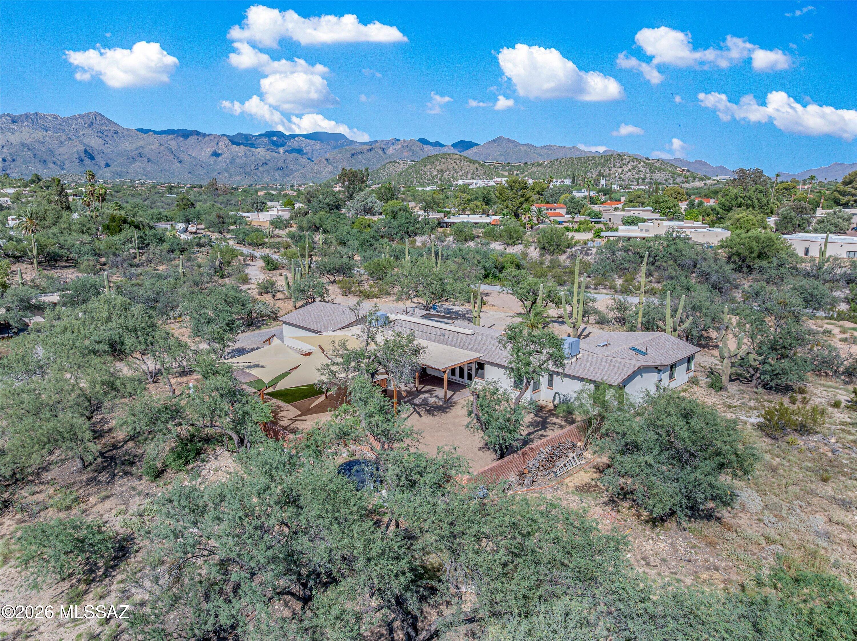 Discover a unique blend of space, privacy, and desert living on 4.01 acres in the lower Foothills with a private well, natural desert landscaping, and mountain views. The beautifully remodeled main home offers light filled living spaces, a warm fireplace, and guest bedrooms with vaulted wood-and-beam ceilings. The kitchen features a large center island, gas stove, and high-end stainless steel appliances. Outside, enjoy an expansive covered patio with pavers, shaded enclosed yard, and custom built-in BBQ with a rustic metal finish. A separate guest house offers space for family, visitors, or potential rental income. BASIS Tucson North, ranked the #1 high school in the country, is just minutes away. Adjoining 5.38 acre also avail., purchase to establish a sprawling estate of just under 10 AC