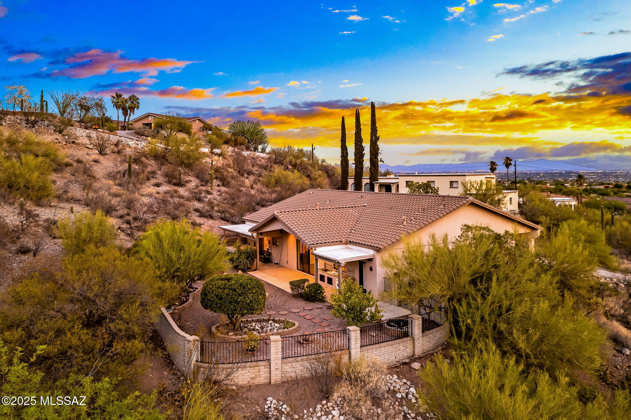 Seller offering a $5,000 Closing Credit with acceptable offer! Perched high in the sought-after North Tucson Foothills, this stunning ranch-style home offers a rare blend of panoramic city light views, sweeping mountain vistas, and peaceful desert living. From sunrise over the Catalinas to sparkling skyline nights, every window frames a breathtaking desert masterpiece. With 2,351 square feet of thoughtfully redesigned living space on nearly an acre, the property captures sweeping mountain views, twinkling city lights, and the quiet charm of saguaros lining the hillside. Inside, every detail has been elevated with timeless finishes. Warm porcelain wood-look tile stretches throughout, while granite counters upgrade every hard surface—including all bathrooms—for a clean, cohesive aestheti The open-concept great room, wired for surround sound and anchored by a sleek gas fireplace, flows into a chef-inspired kitchen featuring KitchenAid stainless steel appliances, gas cooktop, double ovens, tumbled stone backsplash, soft-close cabinetry and an oversized island ideal for everyday living or easy entertaining. A wine fridge, color changing uplighting, a back-lit onyx wall on the bar and a butler's pantry with a second fridge add extra function with flair.

The owner's suite is a retreat featuring a private sliding door to patio, walk-in closet and en-suite bathroom with dual vanity and spacious walk-in shower. Each bedroom is light-filled and spacious, including two guest rooms connected by a stylish Jack & Jill bath with dual vanities and shower/tub combo. All 3 of the stylish full bathrooms feature granite countertops and skirted executive height toilets with soft close seats.

Step outside to enjoy the desert's best show - Tucson's golden sunsets and starry skies. Host al fresco in your outdoor kitchen with an electric cooktop, oven and sink, or relax in the hot tub as the Catalina Mountains frame your view.

Thoughtfully designed and move-in ready, this hilltop bespoke residence is where refined living meets the natural magic of the Sonoran Desert. Come experience it - this is Tucson living at its finest.