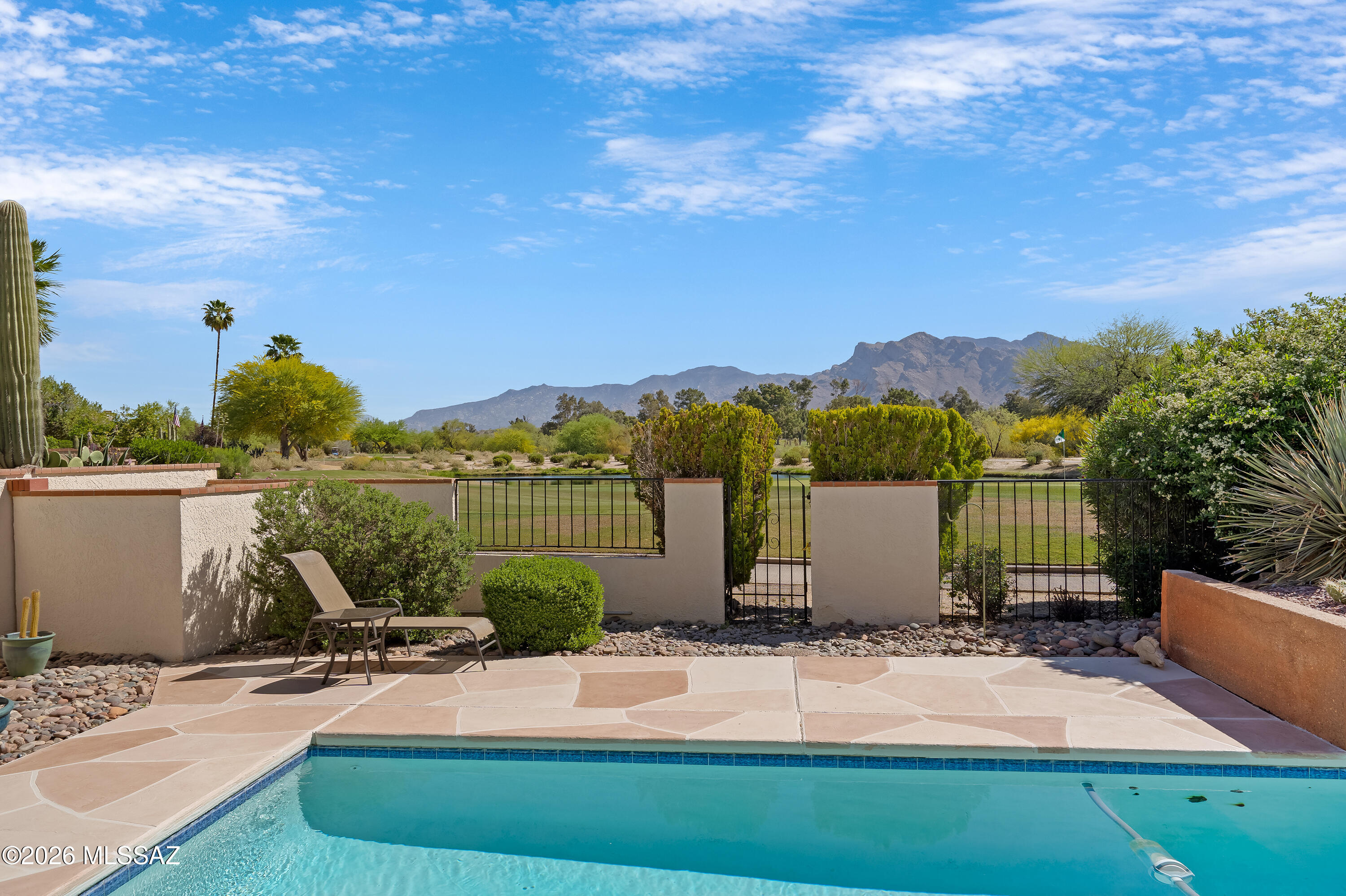 Experience resort-style living in this comfortable townhome, perfectly positioned on the 6th green of the renowned Sonoran Course at Omni Tucson National. This residence captures the essence of desert luxury with soaring ceilings, elegant transom windows, and strategic skylights that bathe the interior in natural light.  The thoughtfully split-bedroom floor plan ensures maximum privacy for you and your guests. Step outside to your private sanctuary where the backyard faces East, offering a cool, shaded retreat all afternoon. Relax poolside with a cold beverage as you soak in breathtaking, unobstructed views of the majestic Catalina Mountains. A spacious two-car garage featuring custom built-in cabinetry provides ample storage for an organized, refined lifestyle.